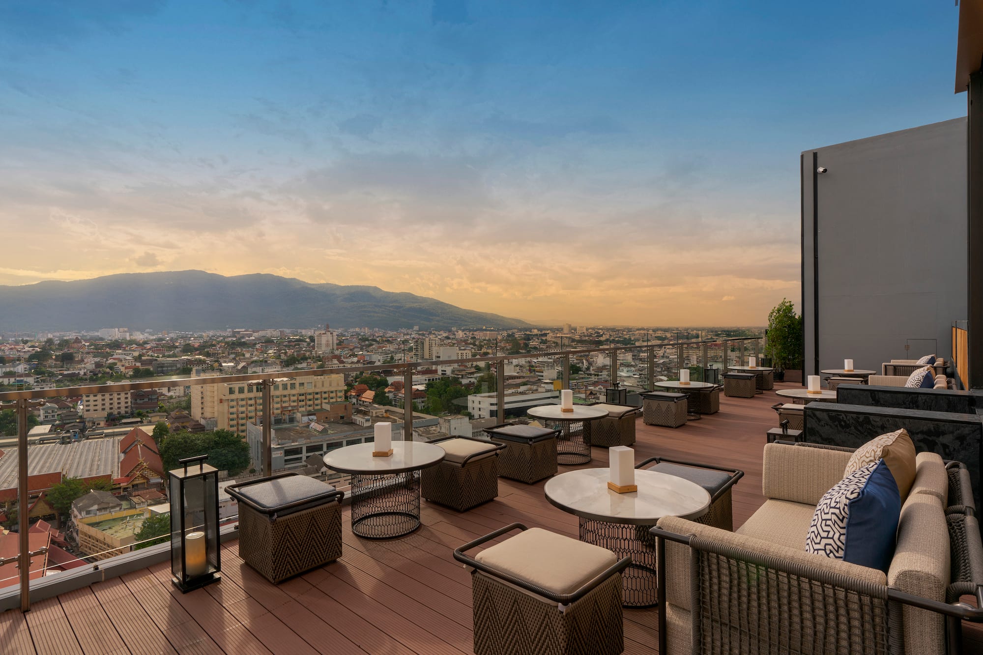 Rooftop bar with city and mountain views at sunset. Outdoor lounge.