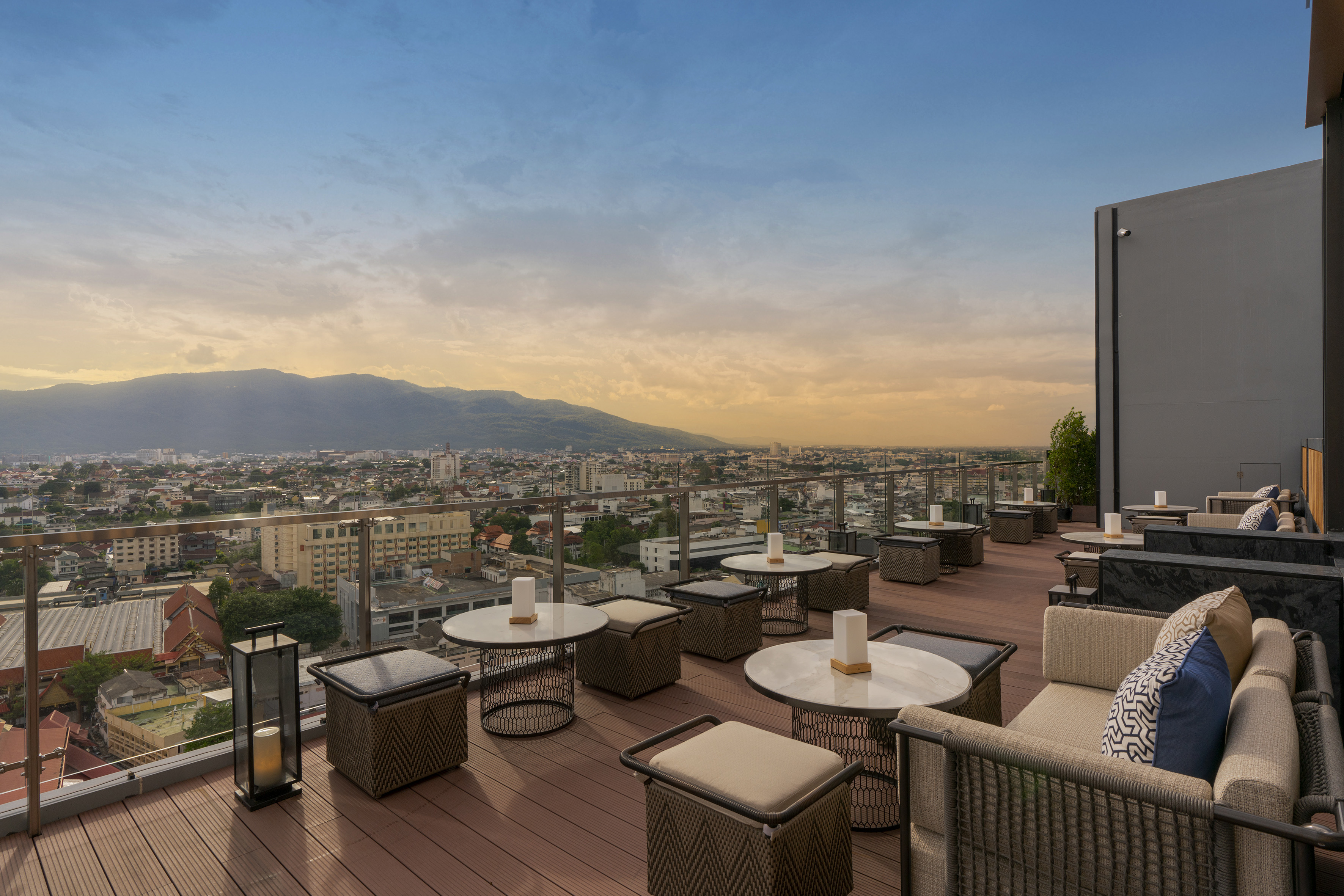 Rooftop bar with city and mountain views at sunset. Outdoor lounge.