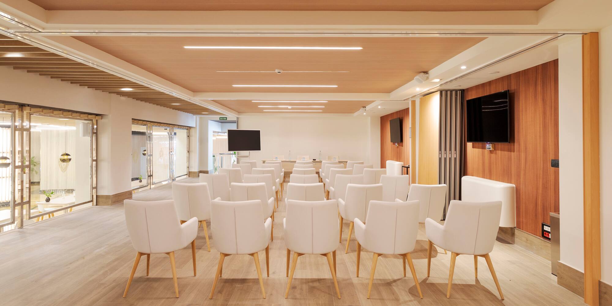 a room with white chairs and a television