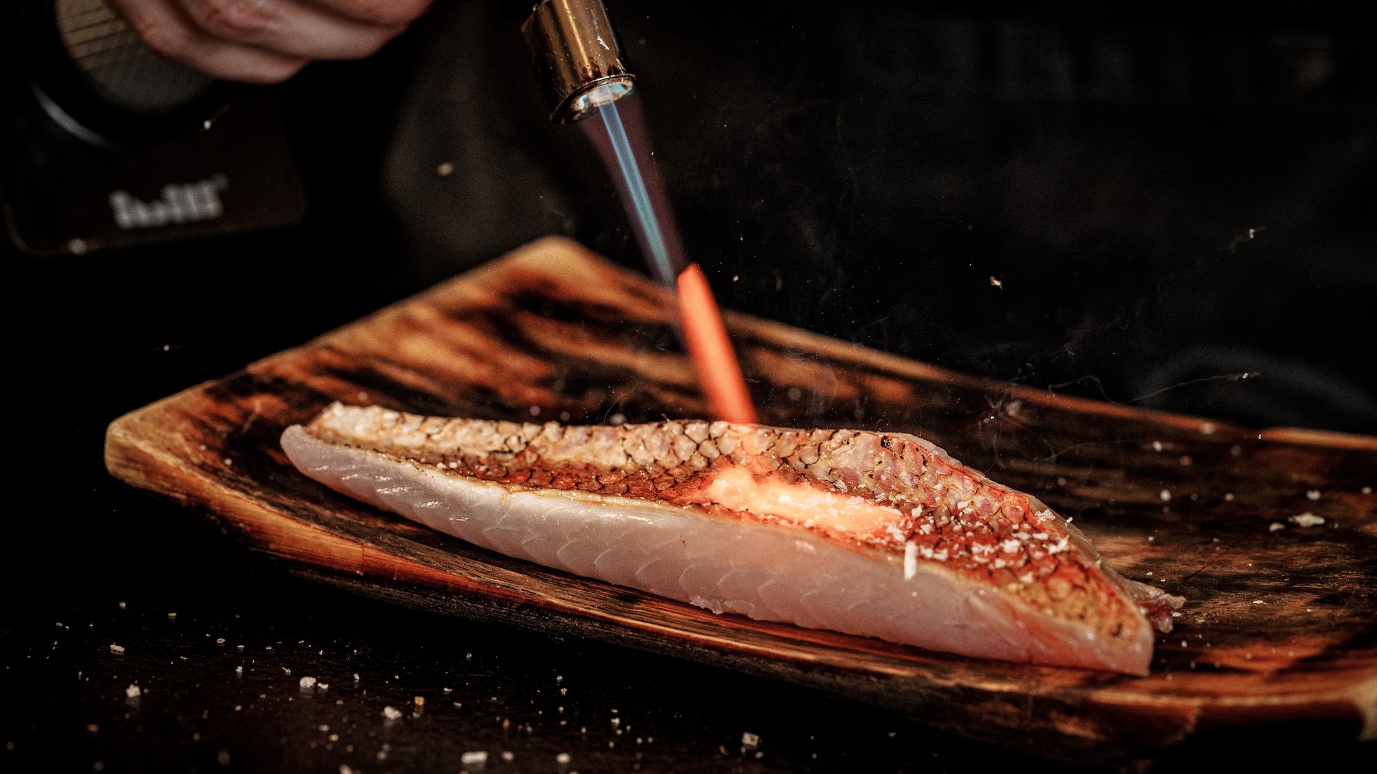 a person lighting a piece of fish