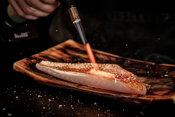 a person lighting a piece of fish