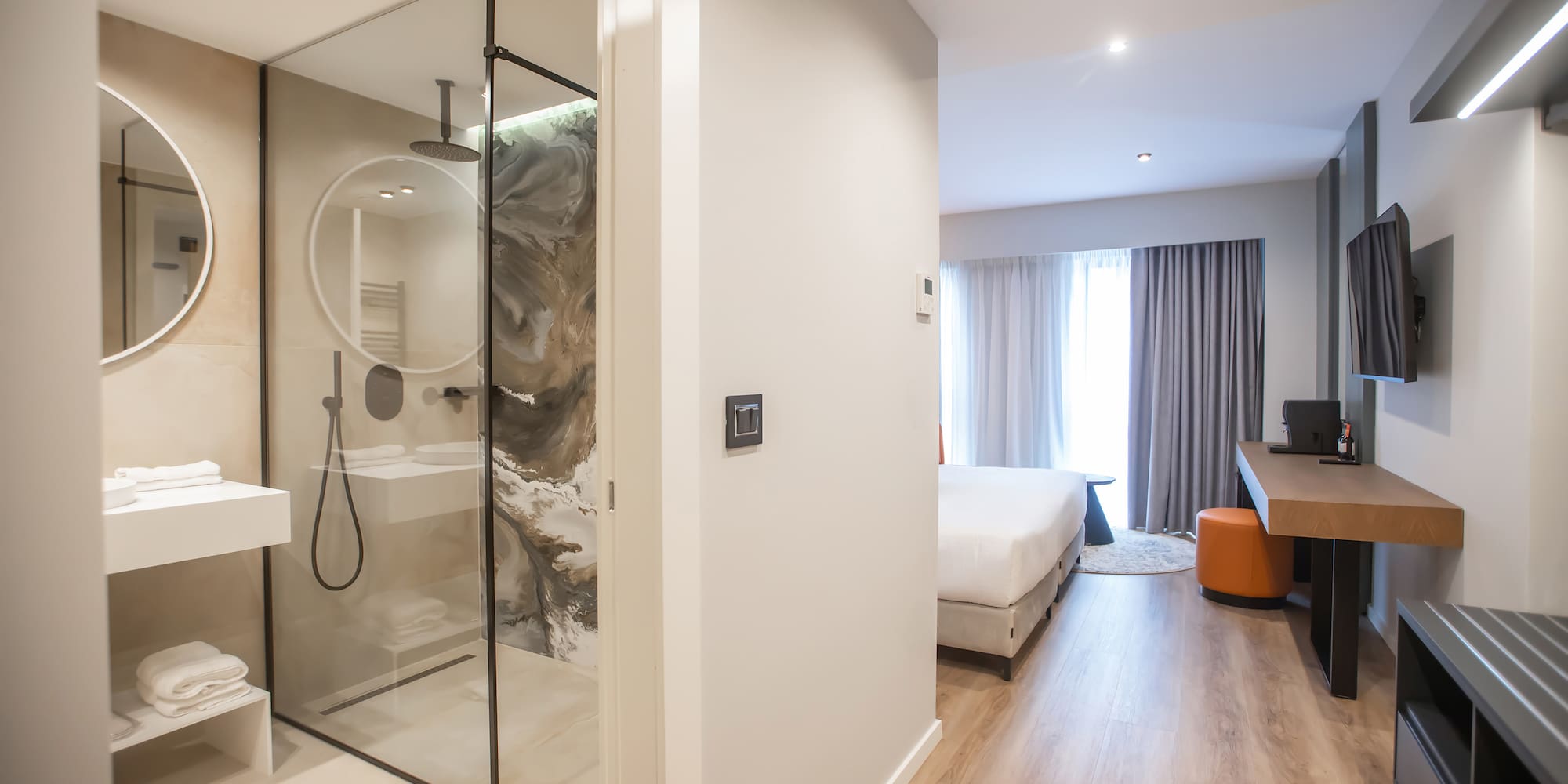 a bathroom with a glass shower and a bed