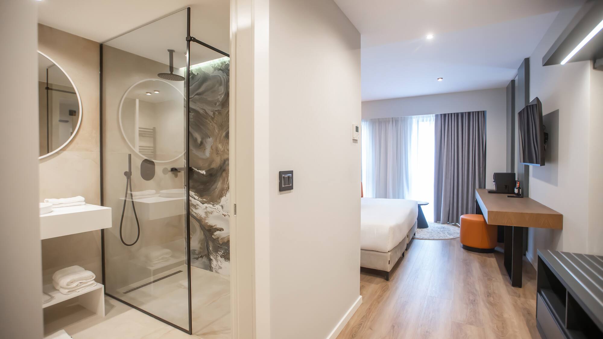 a bathroom with a glass shower and a bed