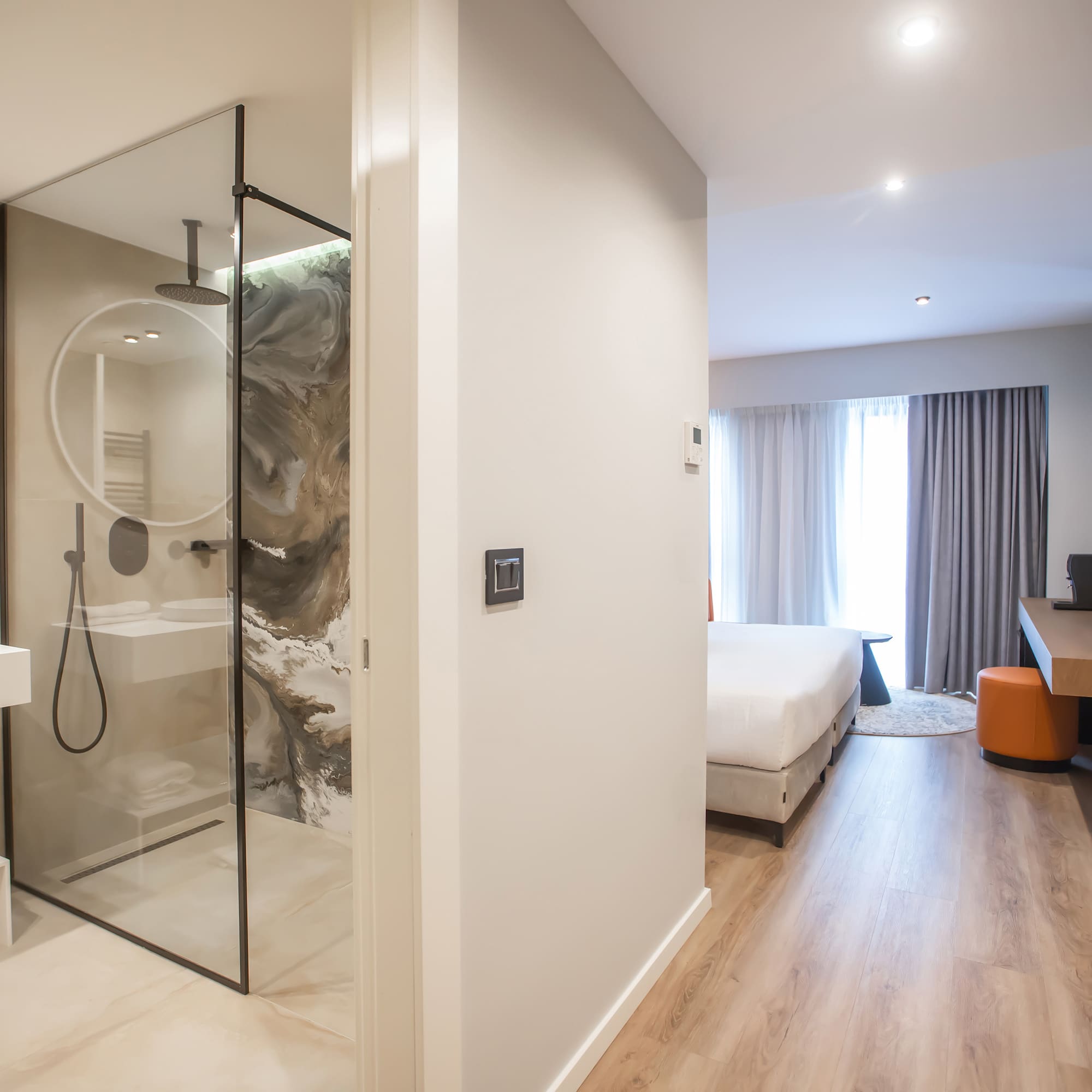 a bathroom with a glass shower and a bed