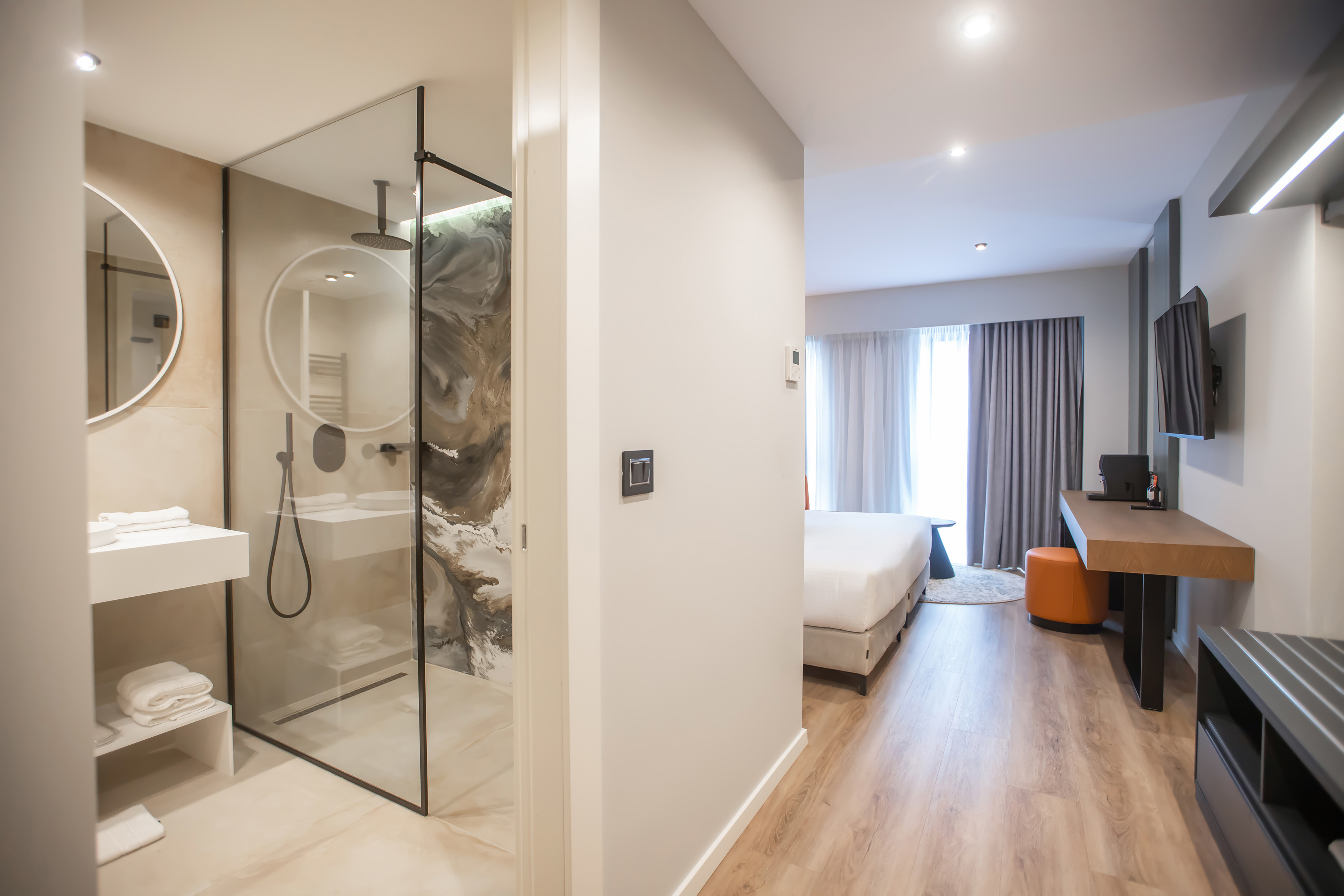 a bathroom with a glass shower and a bed