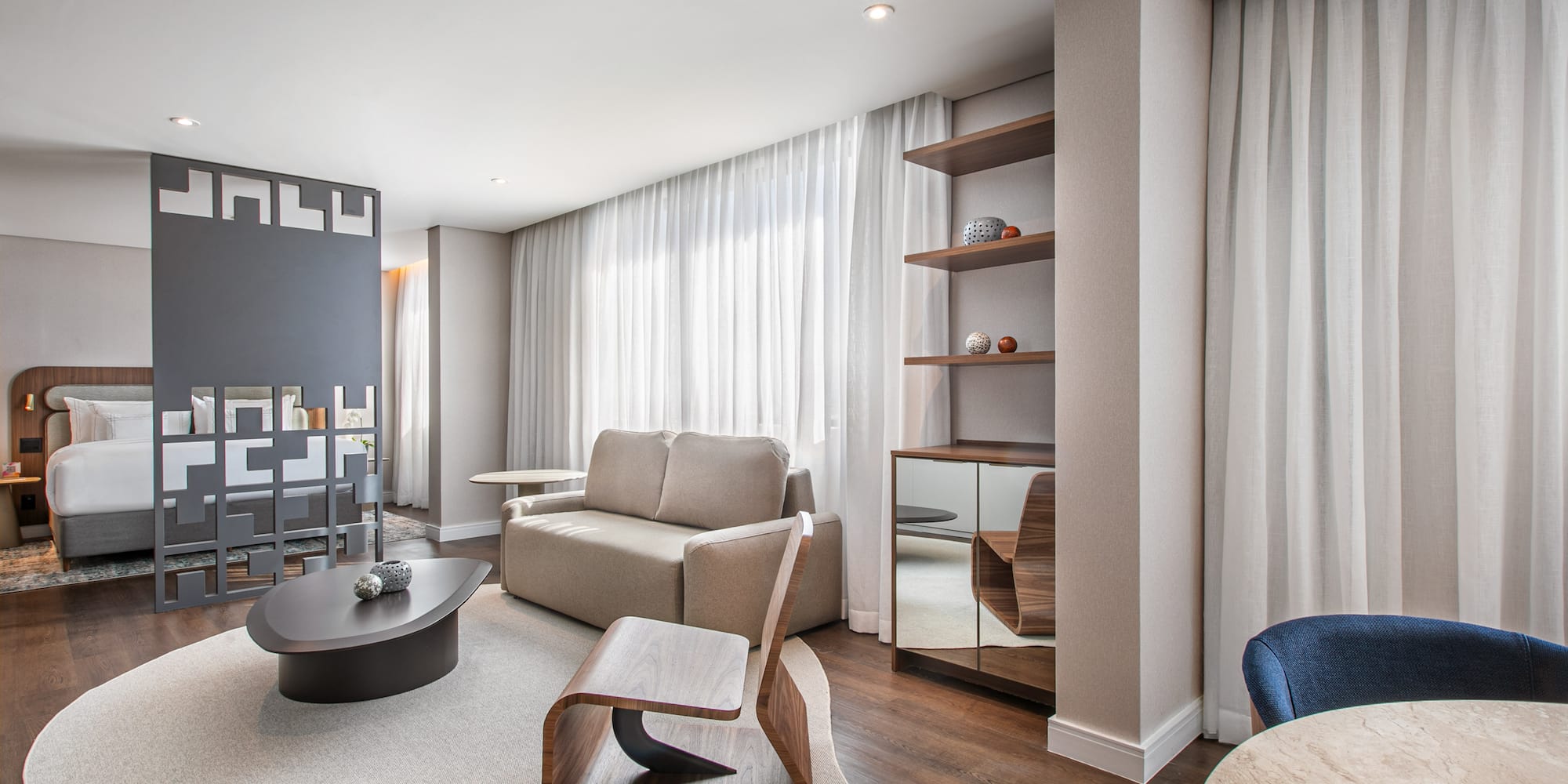 Modern hotel suite living area with sofa, coffee table, and integrated bedroom.