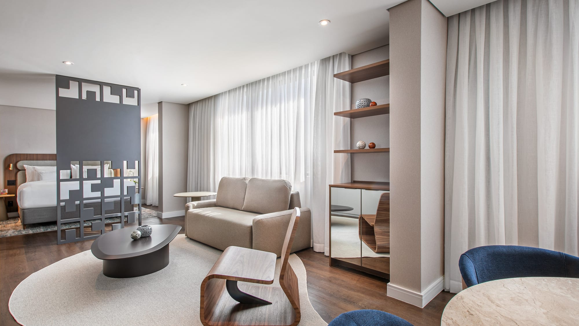 Modern hotel suite living area with sofa, coffee table, and integrated bedroom.