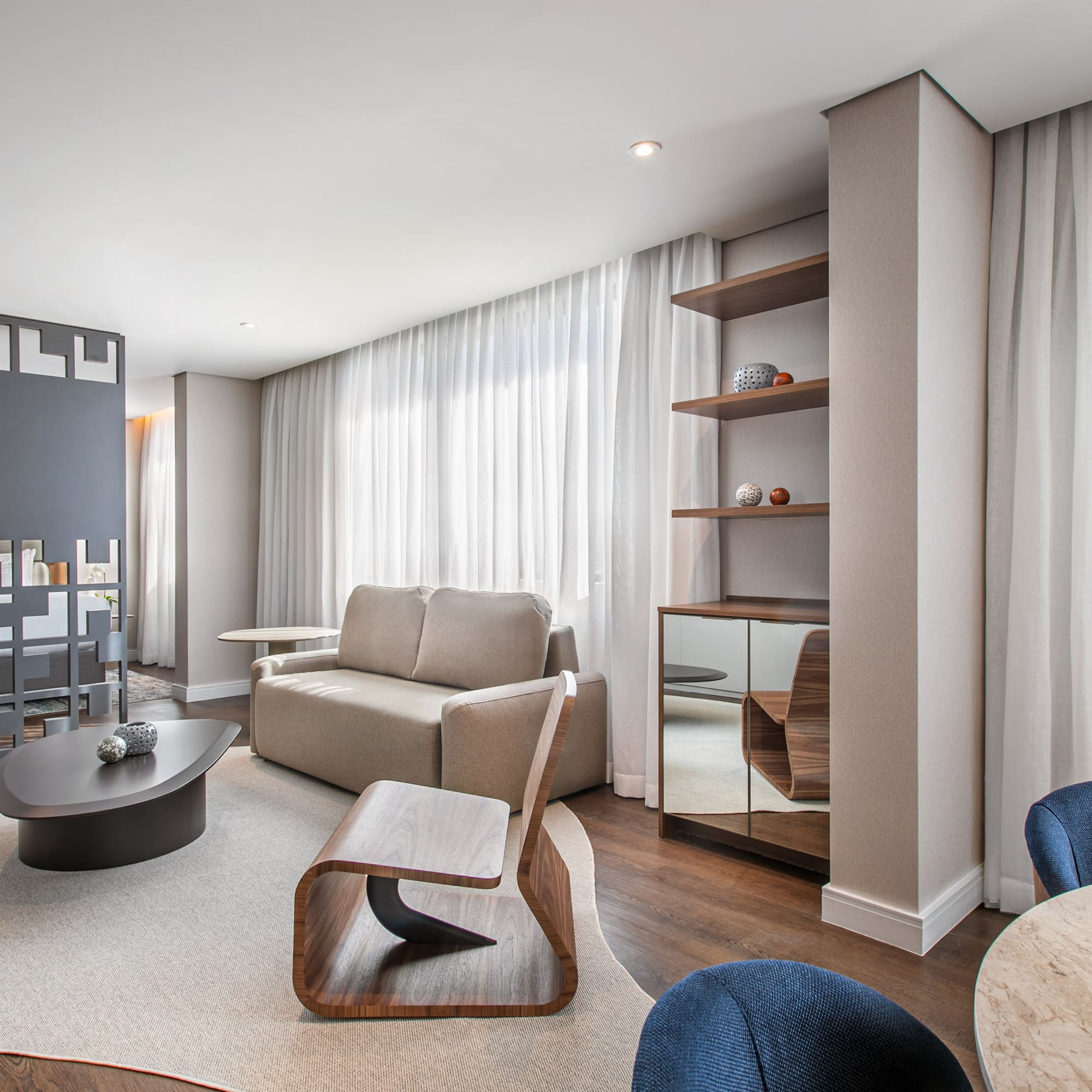 Modern hotel suite living area with sofa, coffee table, and integrated bedroom.