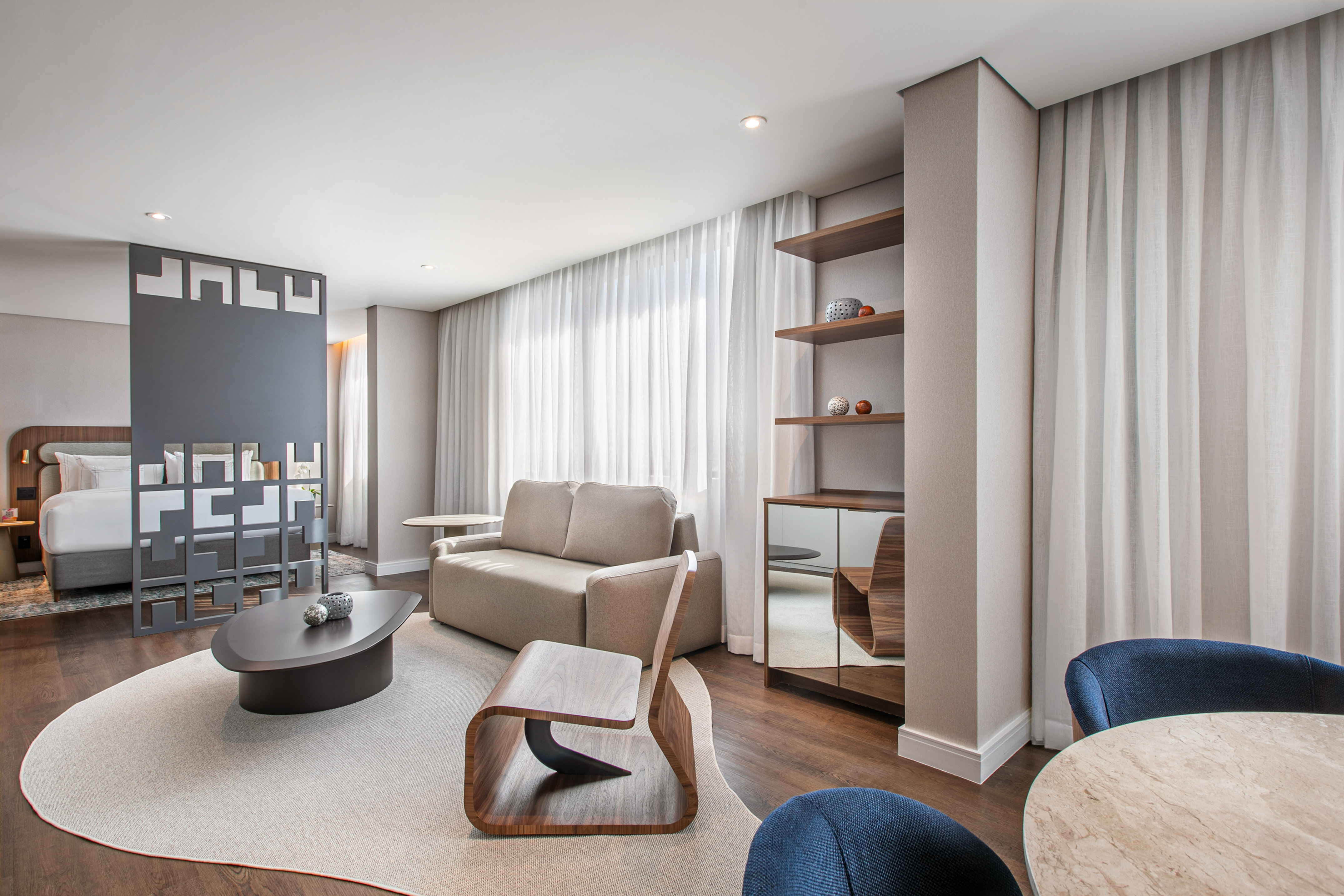 Modern hotel suite living area with sofa, coffee table, and integrated bedroom.