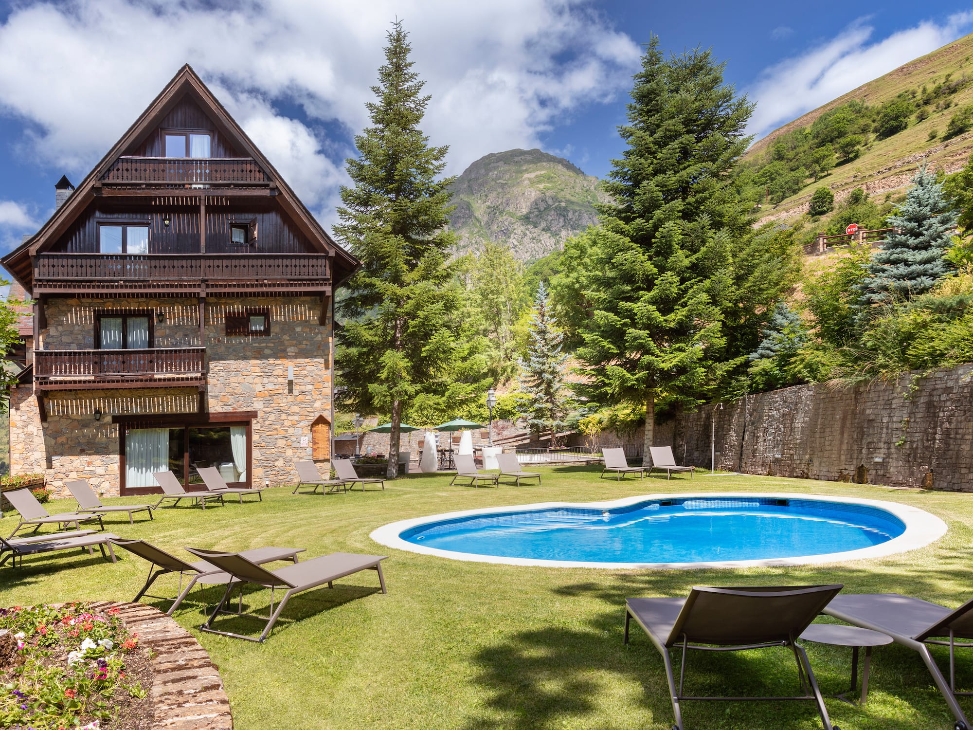 Chalet de montaña con piscina exterior, jardín y vistas a las montañas.