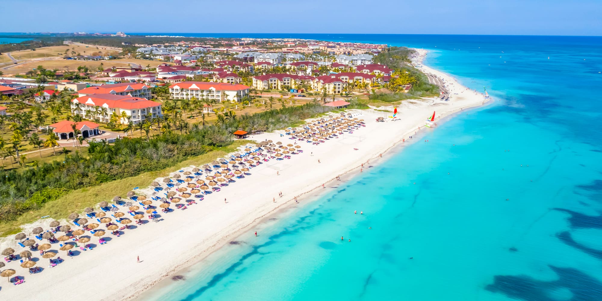 a beach with buildings and blue water