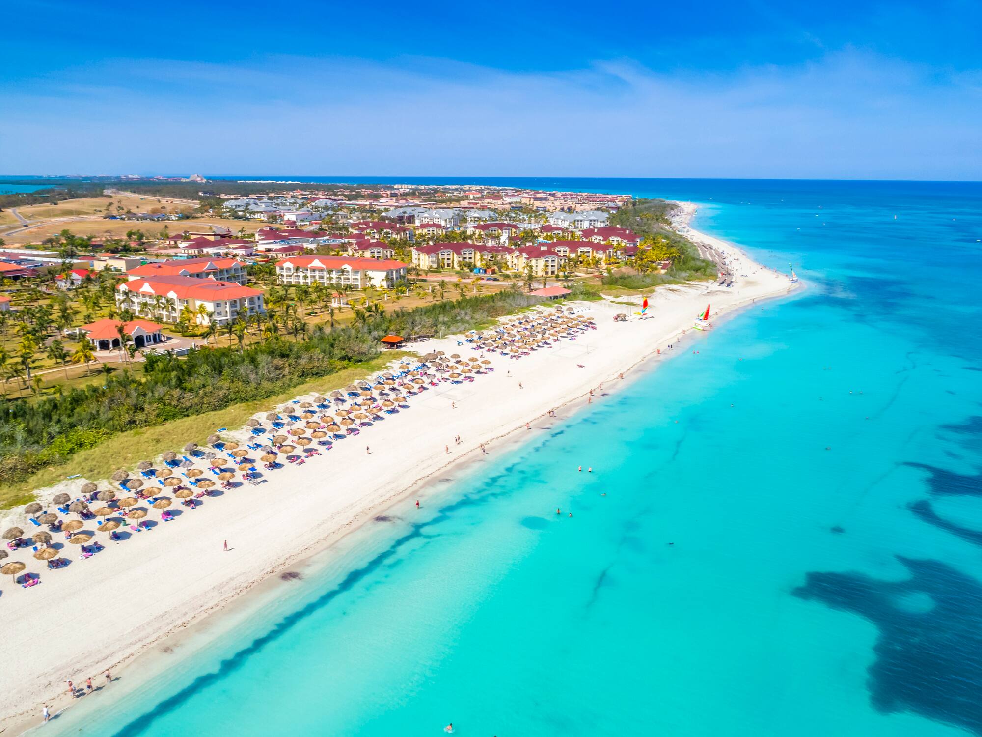 a beach with buildings and blue water