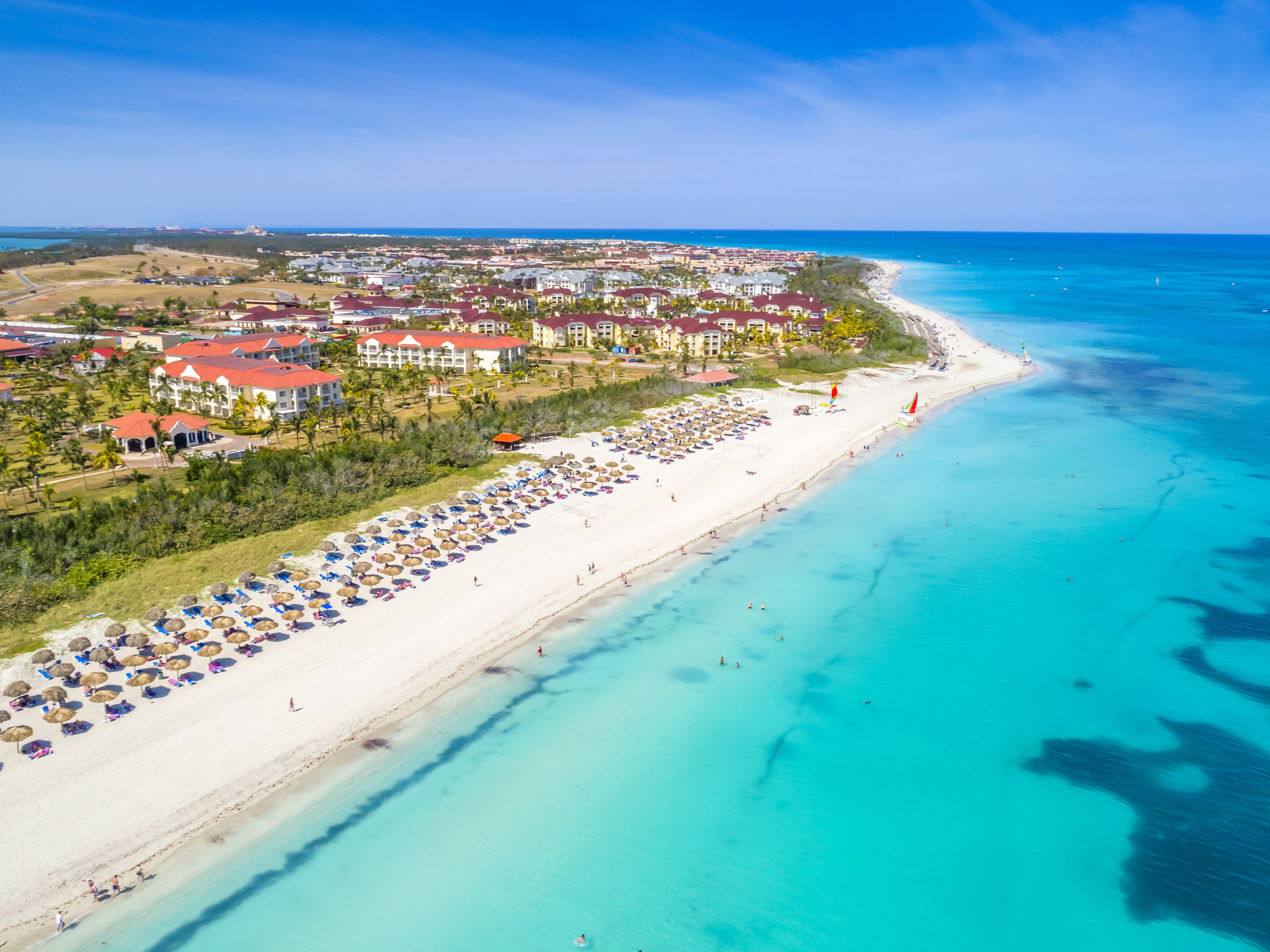 a beach with buildings and blue water