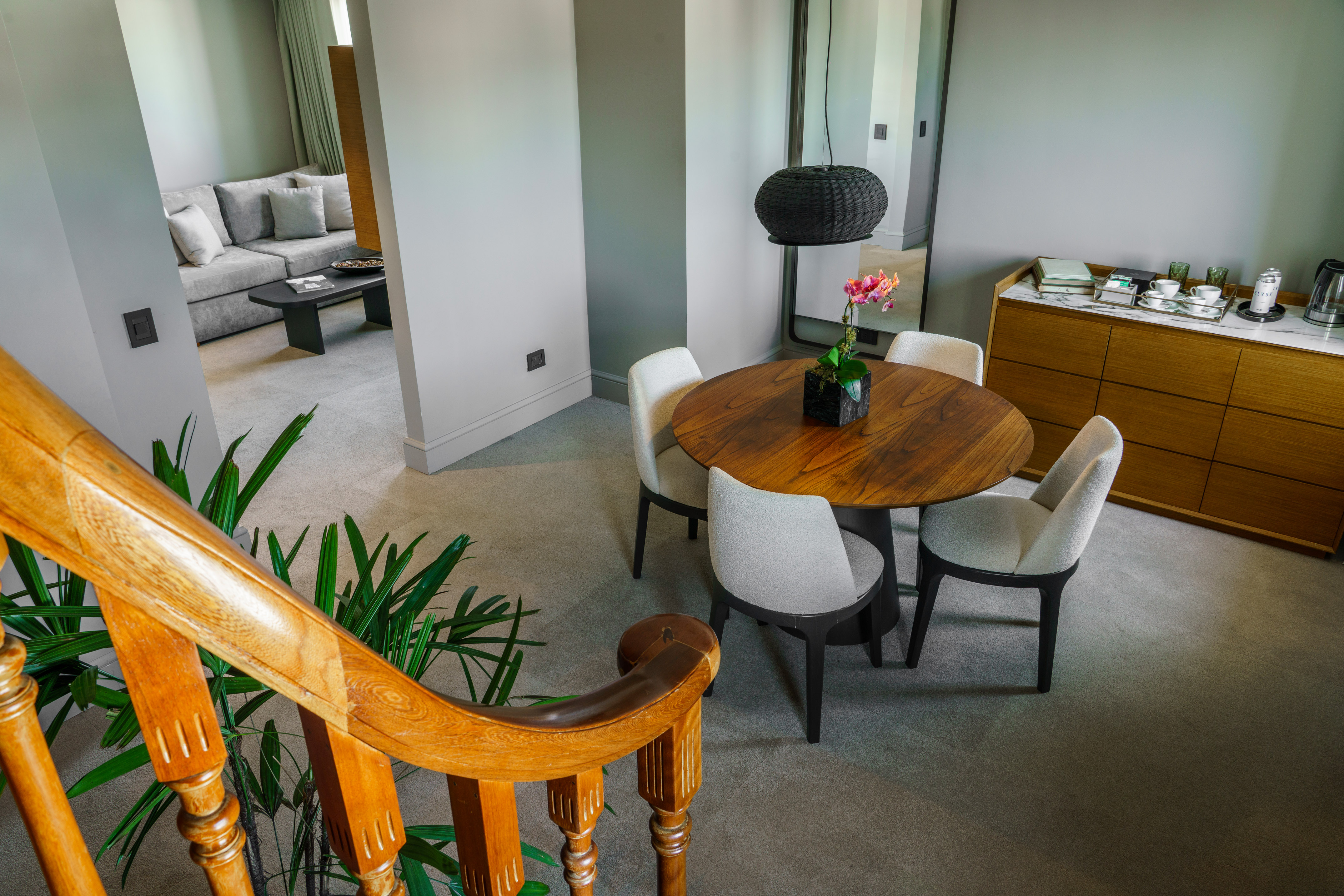 Modern hotel suite interior: dining area, living room, and wooden staircase.
