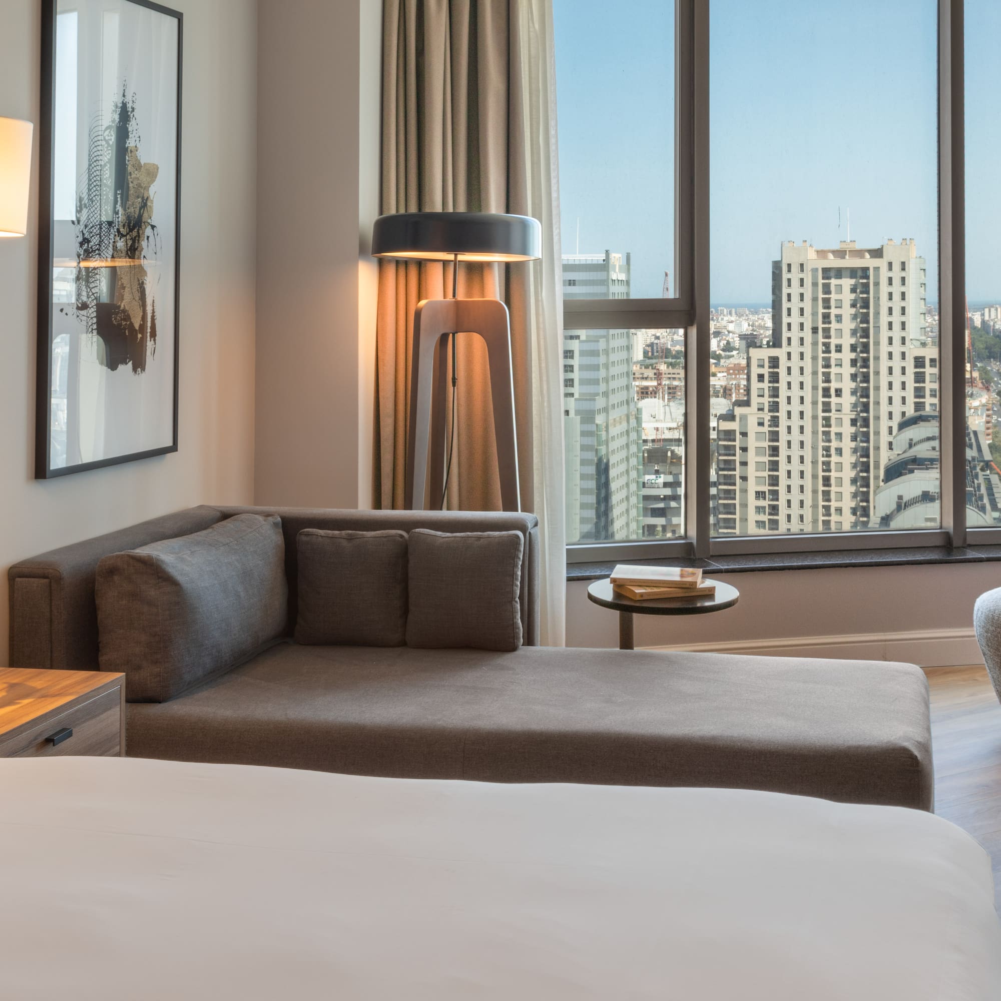 Suite de hotel moderna con sofá, cama y vista panorámica de la ciudad.