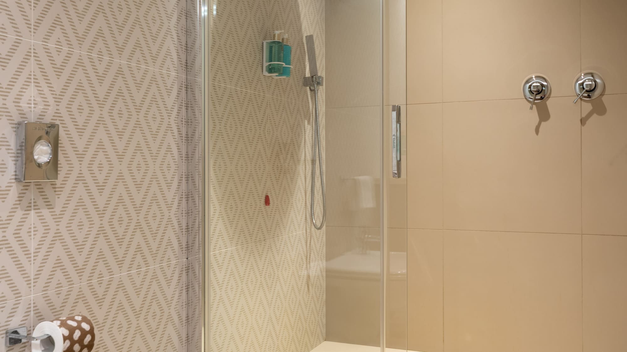 Beige tiled modern bathroom with glass walk-in shower and white toilet.