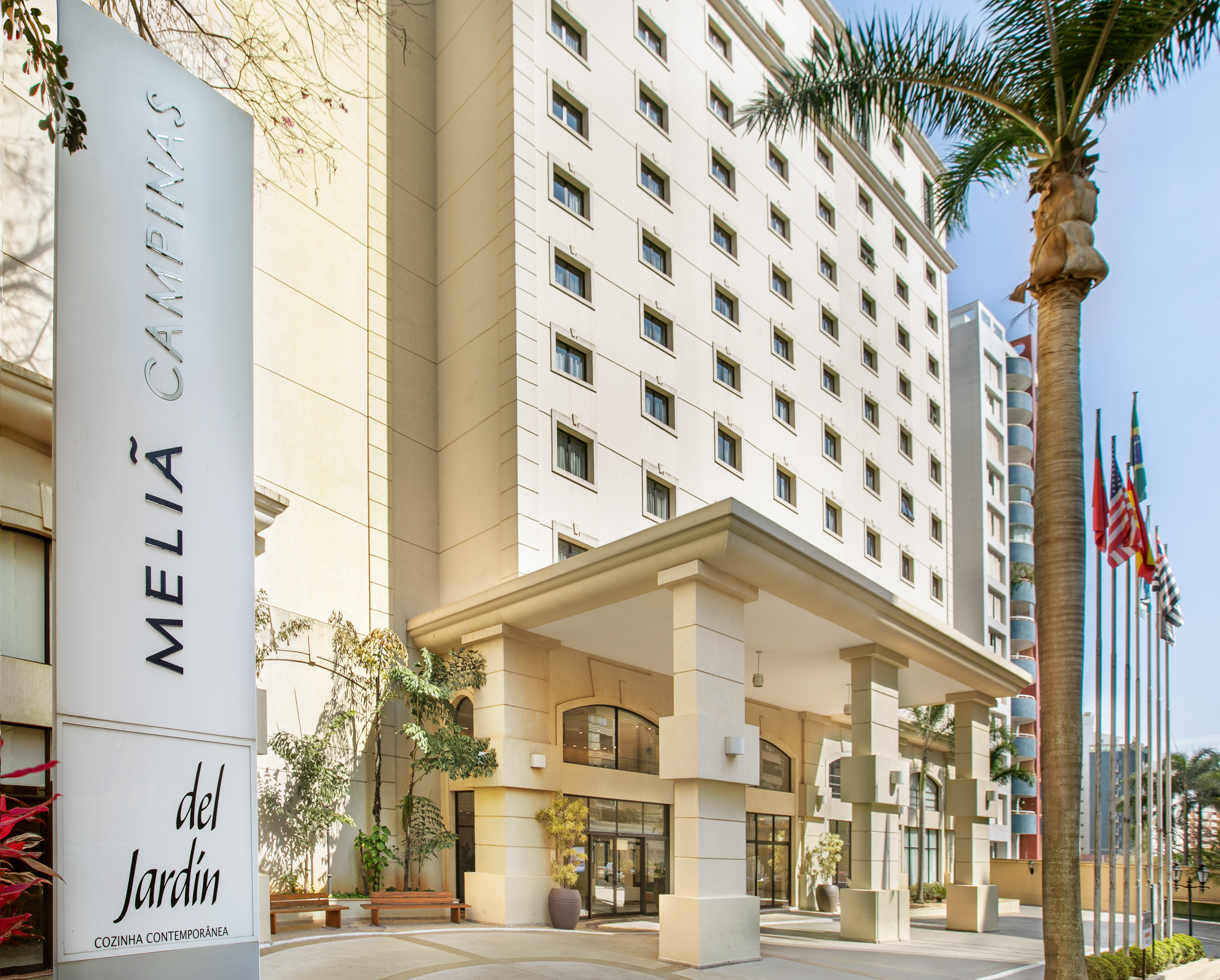 Meliá Campinas hotel entrance and facade with sign, palm trees, and flags. - Meliá Campinas, Campinas