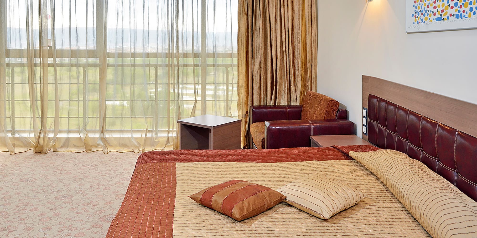 a bed with pillows and a chair in a room with curtains