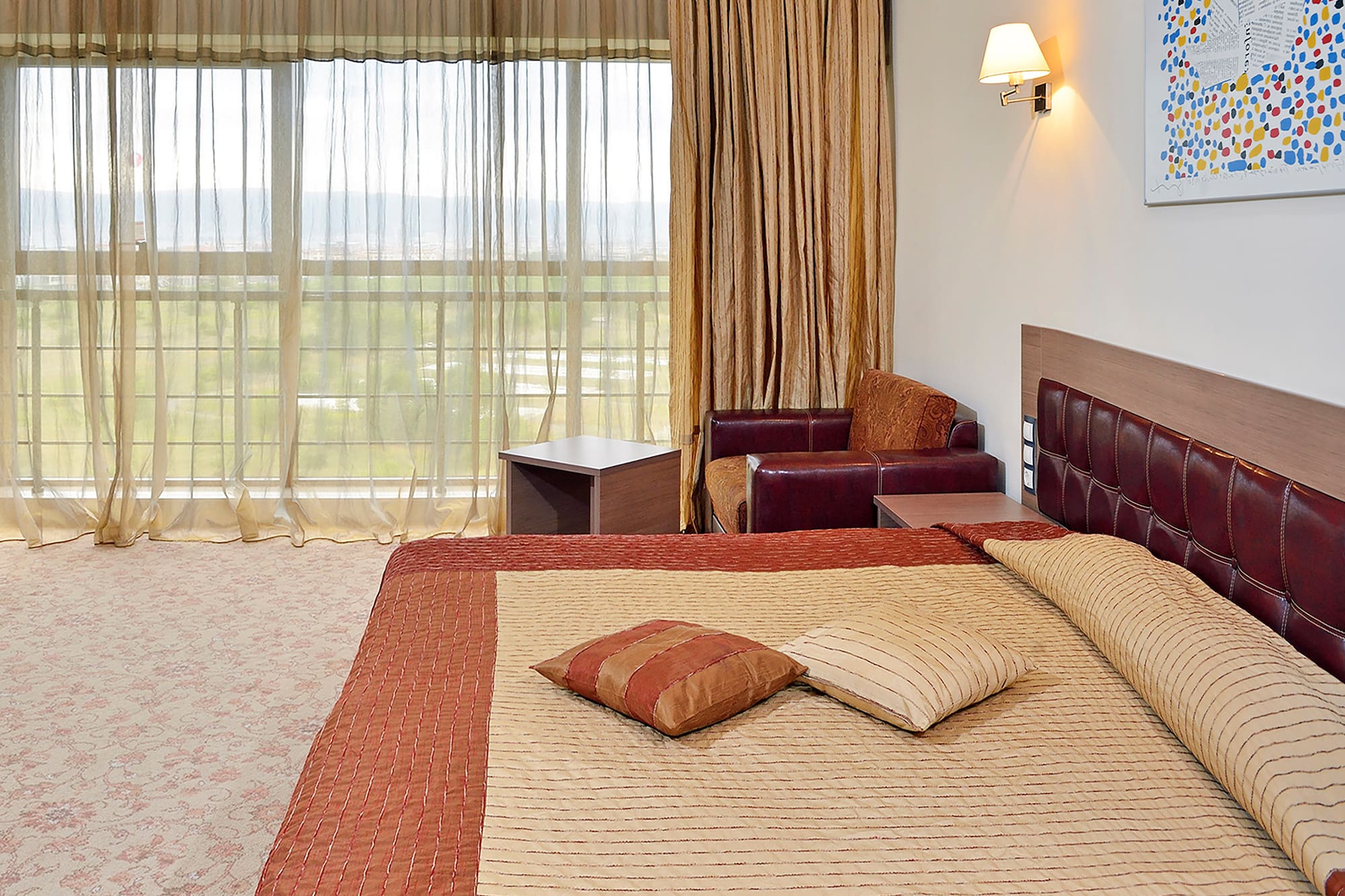 a bed with pillows and a chair in a room with curtains