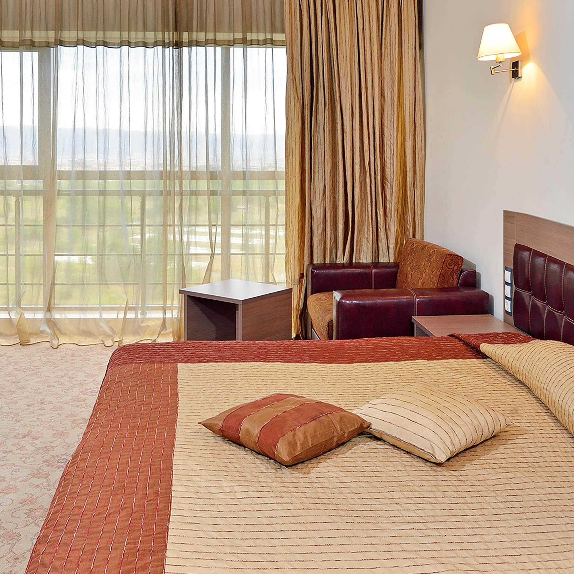 a bed with pillows and a chair in a room with curtains