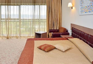 a bed with pillows and a chair in a room with curtains