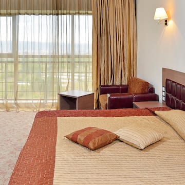 a bed with pillows and a chair in a room with curtains