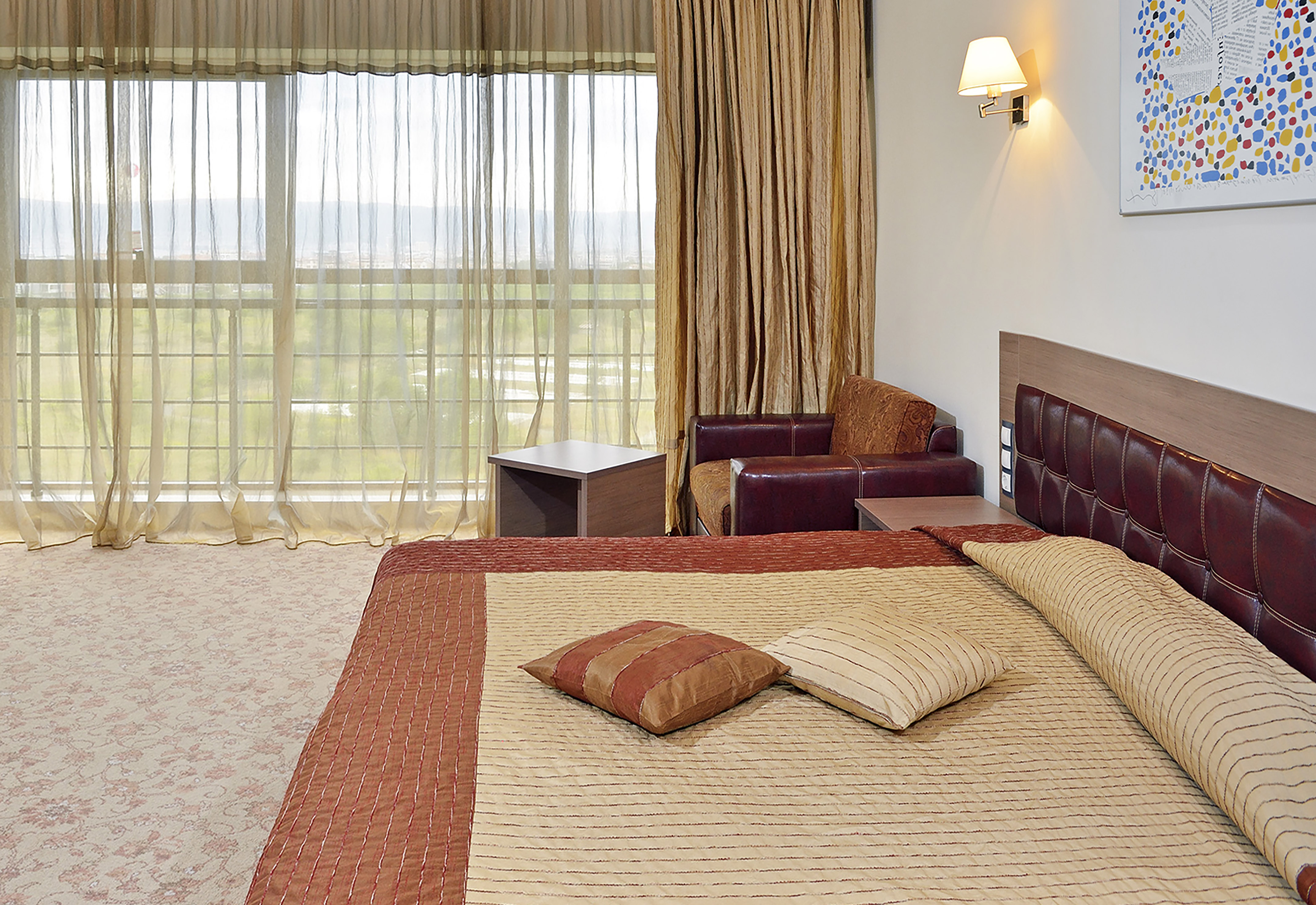 a bed with pillows and a chair in a room with curtains