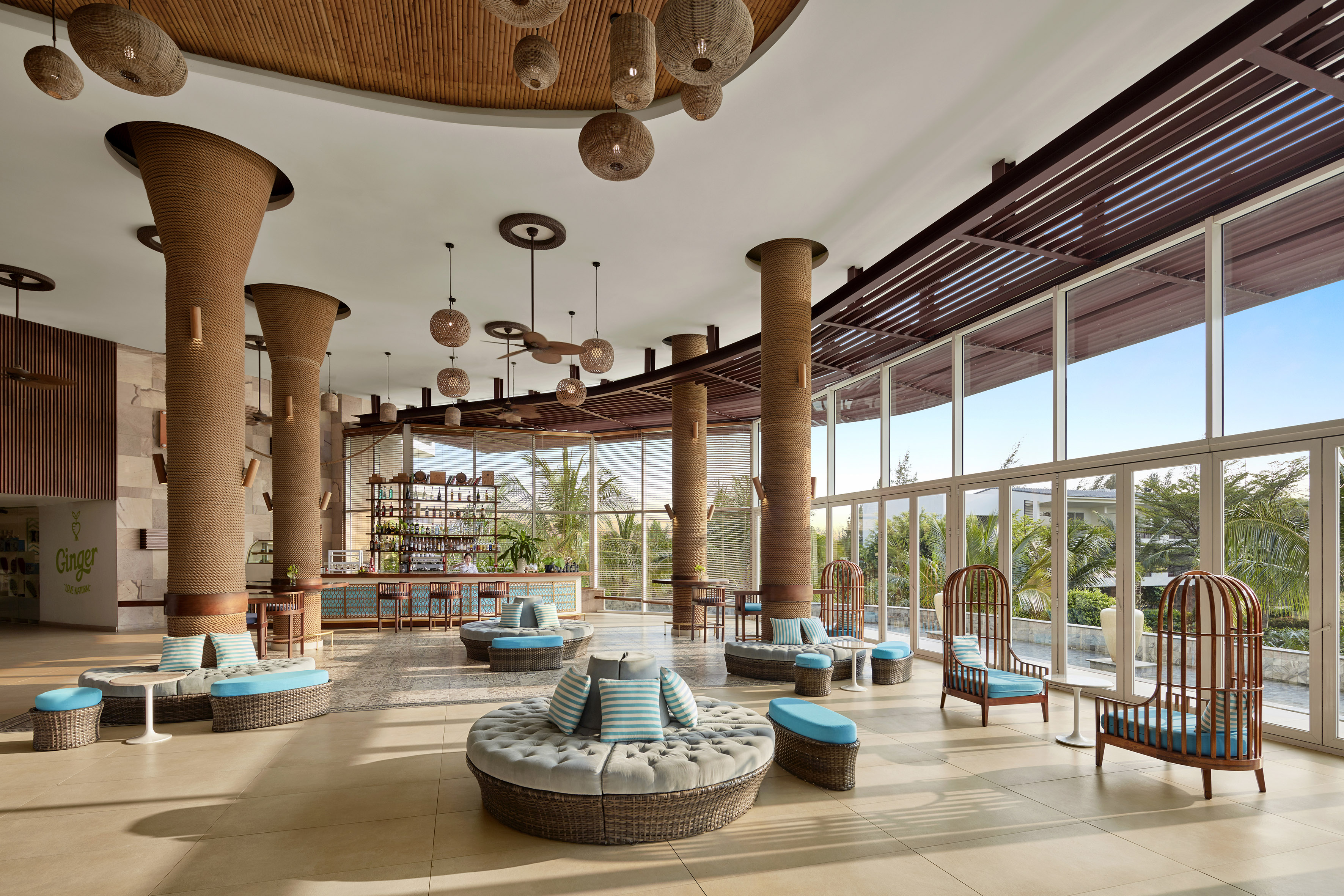 Tropical resort lobby with natural decor, wicker furniture, and large windows.