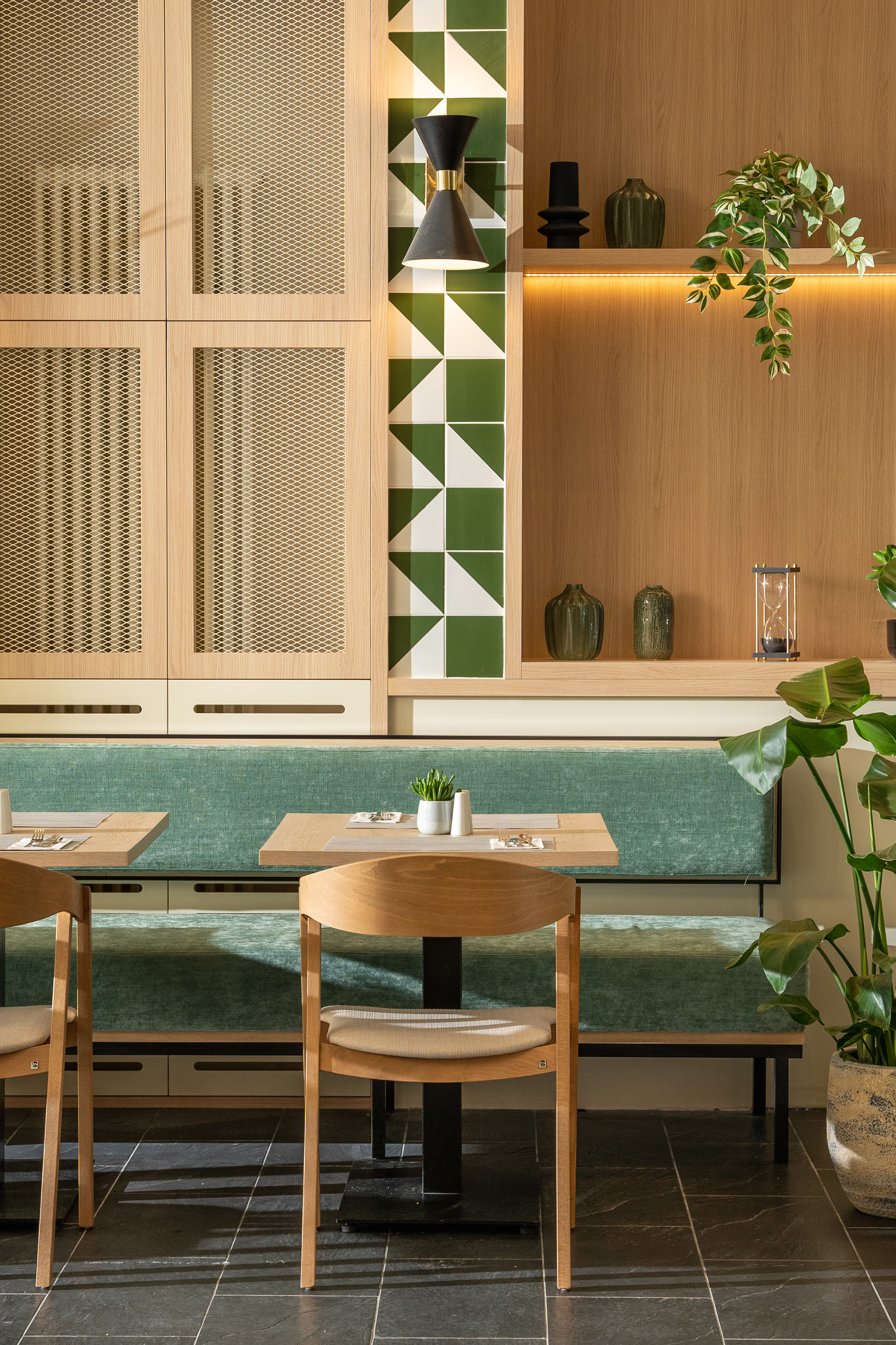 Cafe interior: wood details, green geometric tiles, plush booth seating.