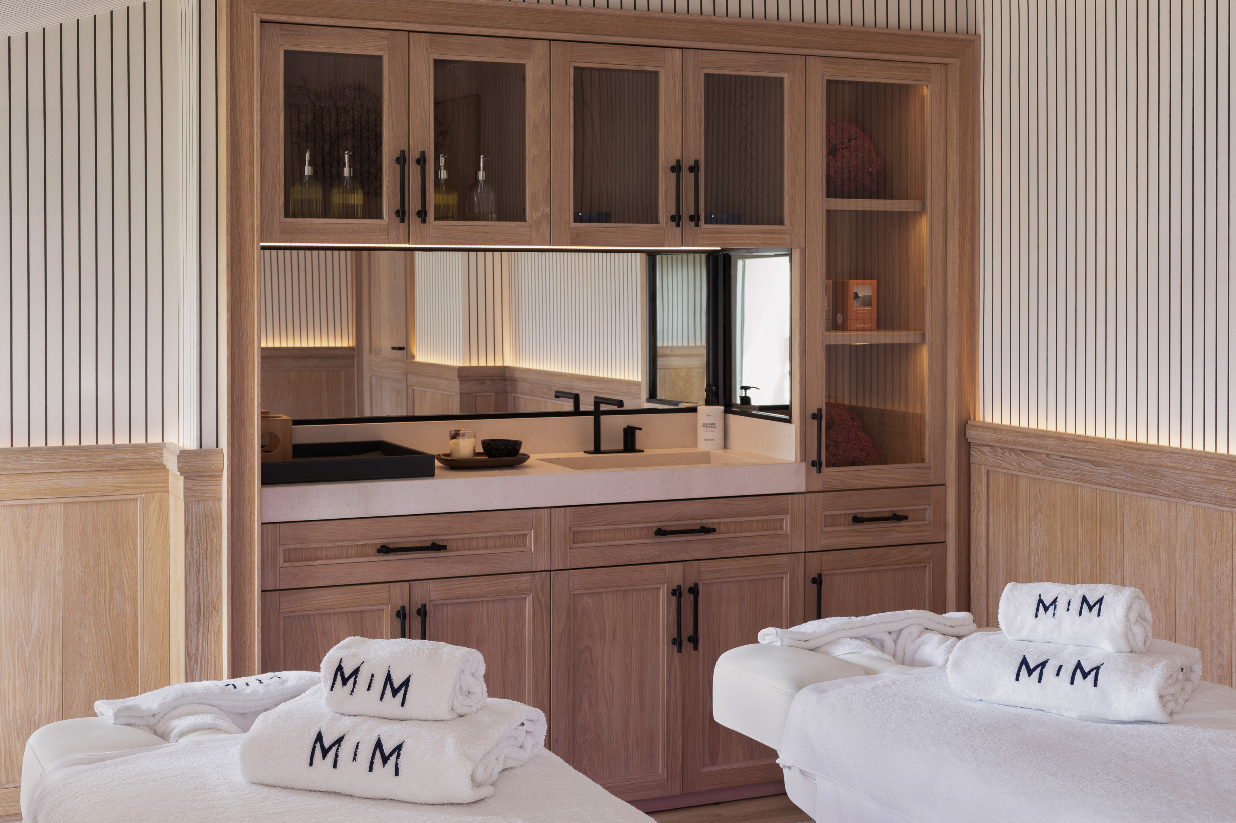 Modern spa treatment room with massage beds, MIM towels, and sleek wood vanity.