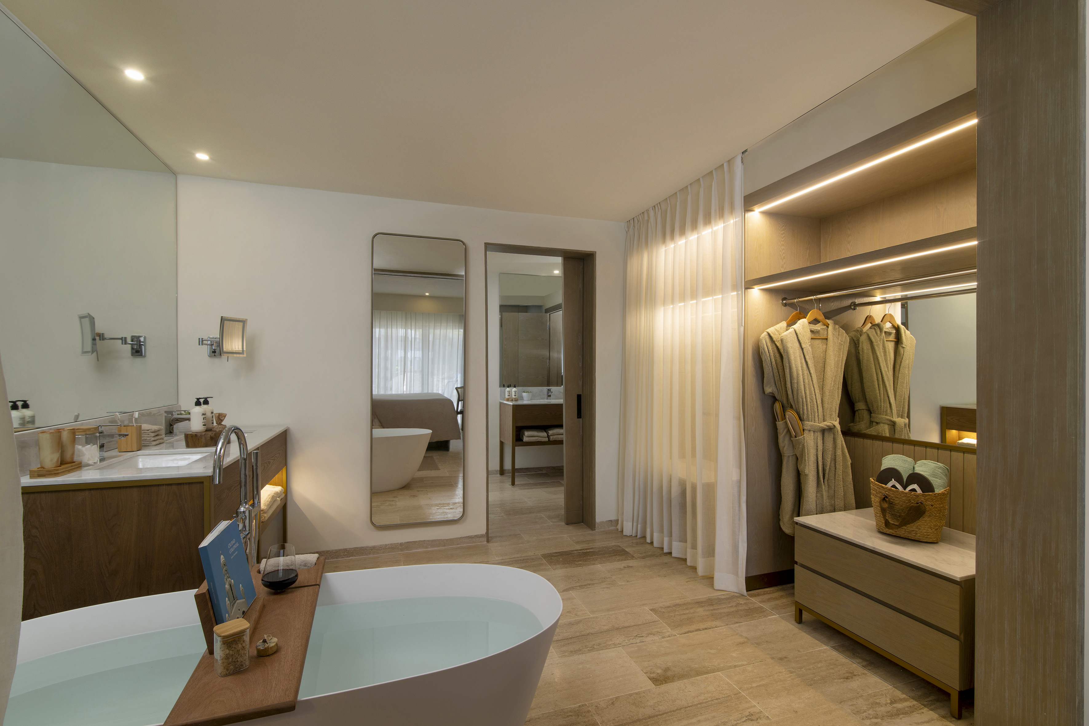 Modern spa bathroom with freestanding tub, dual vanity, and wardrobe.