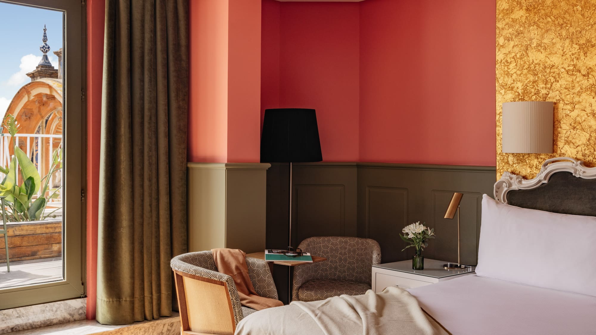 Habitación hotel con balcón, vista a cúpula, interior coral y dorado.