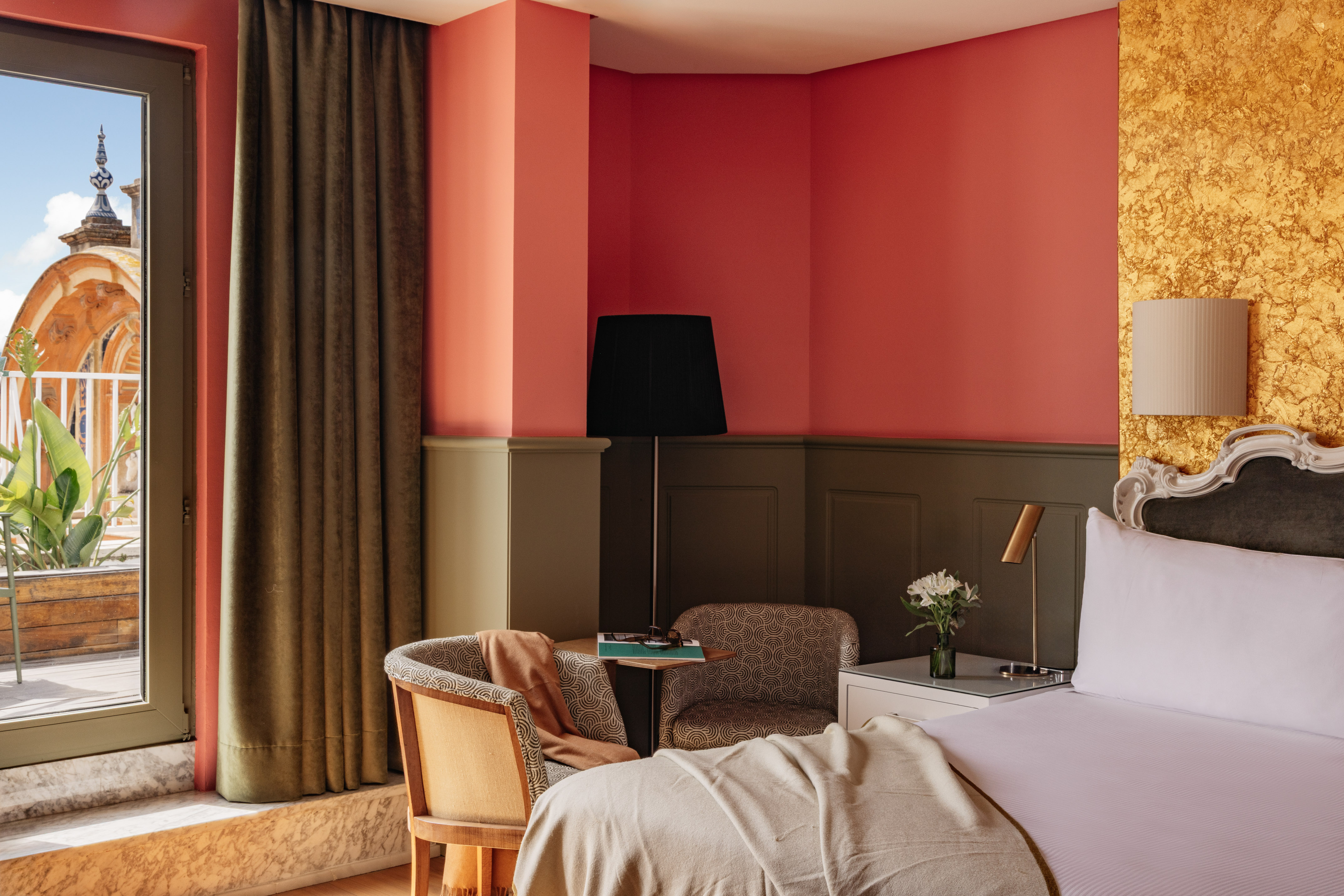 Habitación hotel con balcón, vista a cúpula, interior coral y dorado.