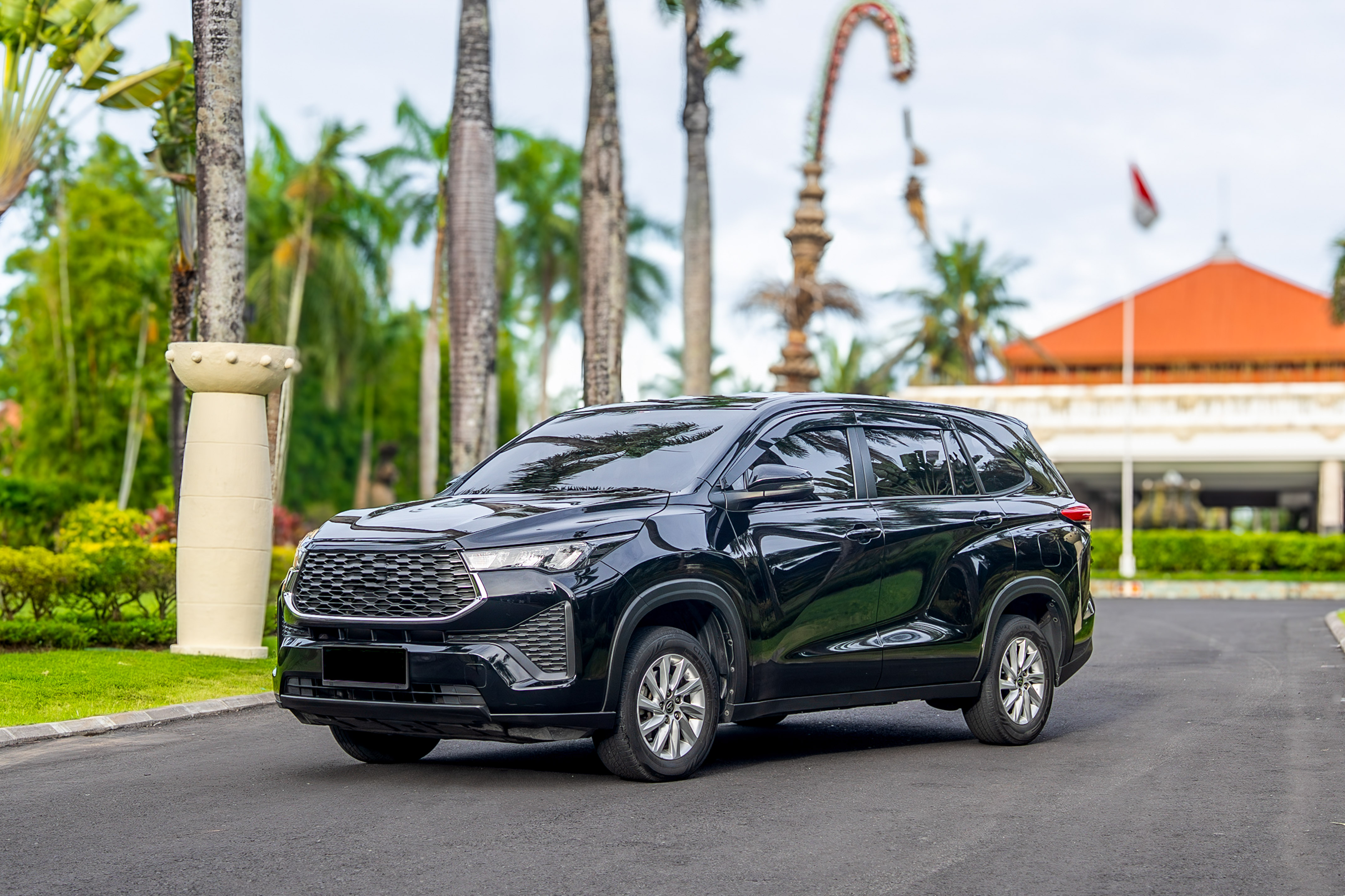 Black modern SUV on a tropical resort driveway with palm trees.