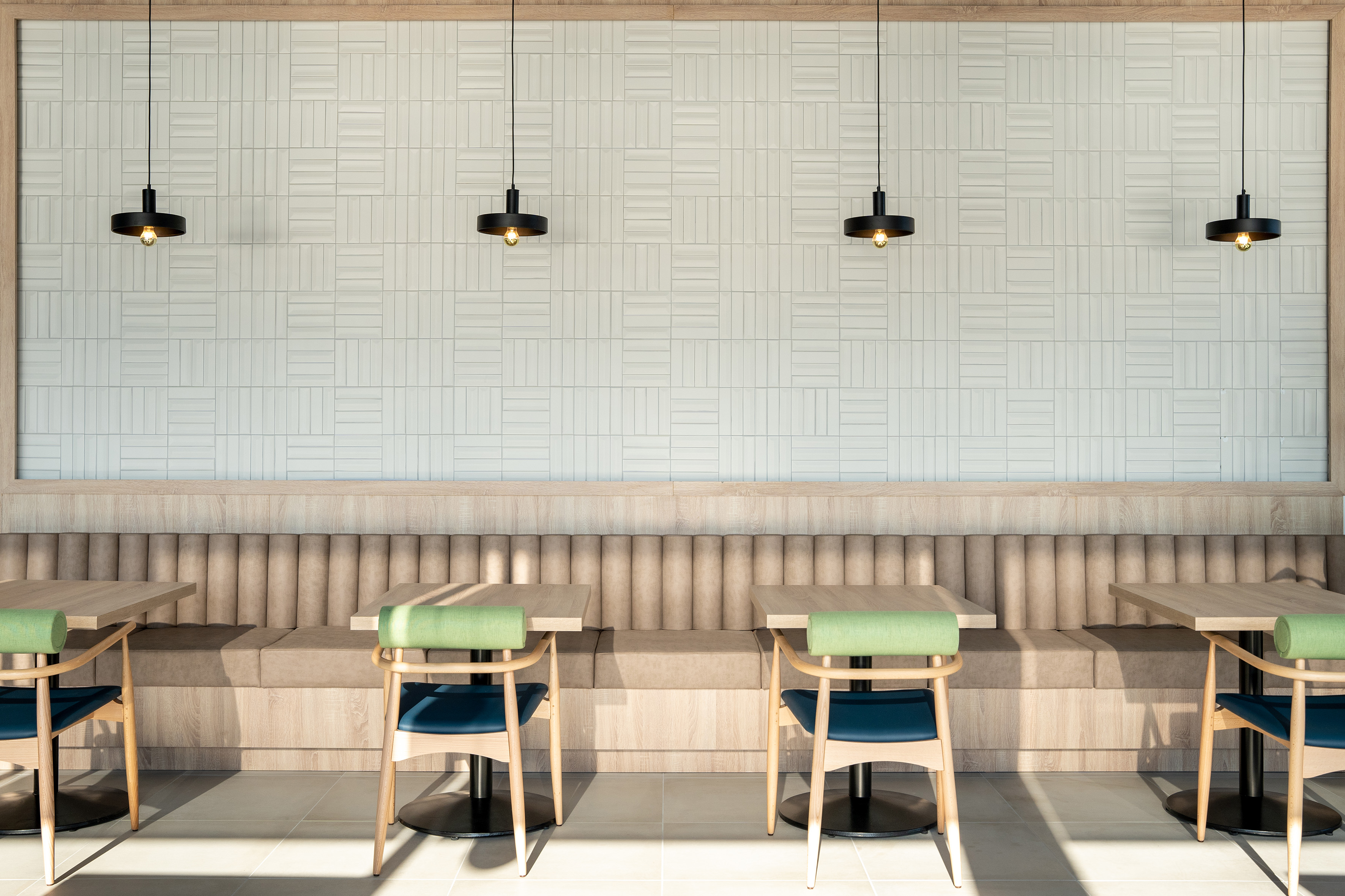 Modern cafe interior with wood tables, banquette seating, and pendant lights.