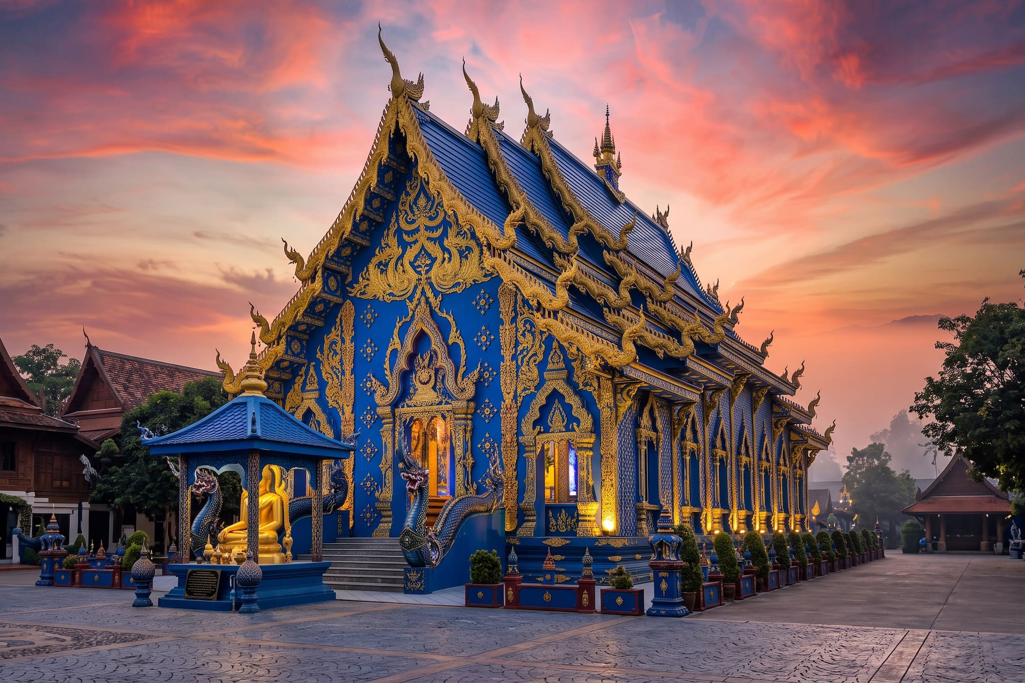 Ornate blue and gold Thai temple (Wat Rong Suea Ten) against a sunset sky.