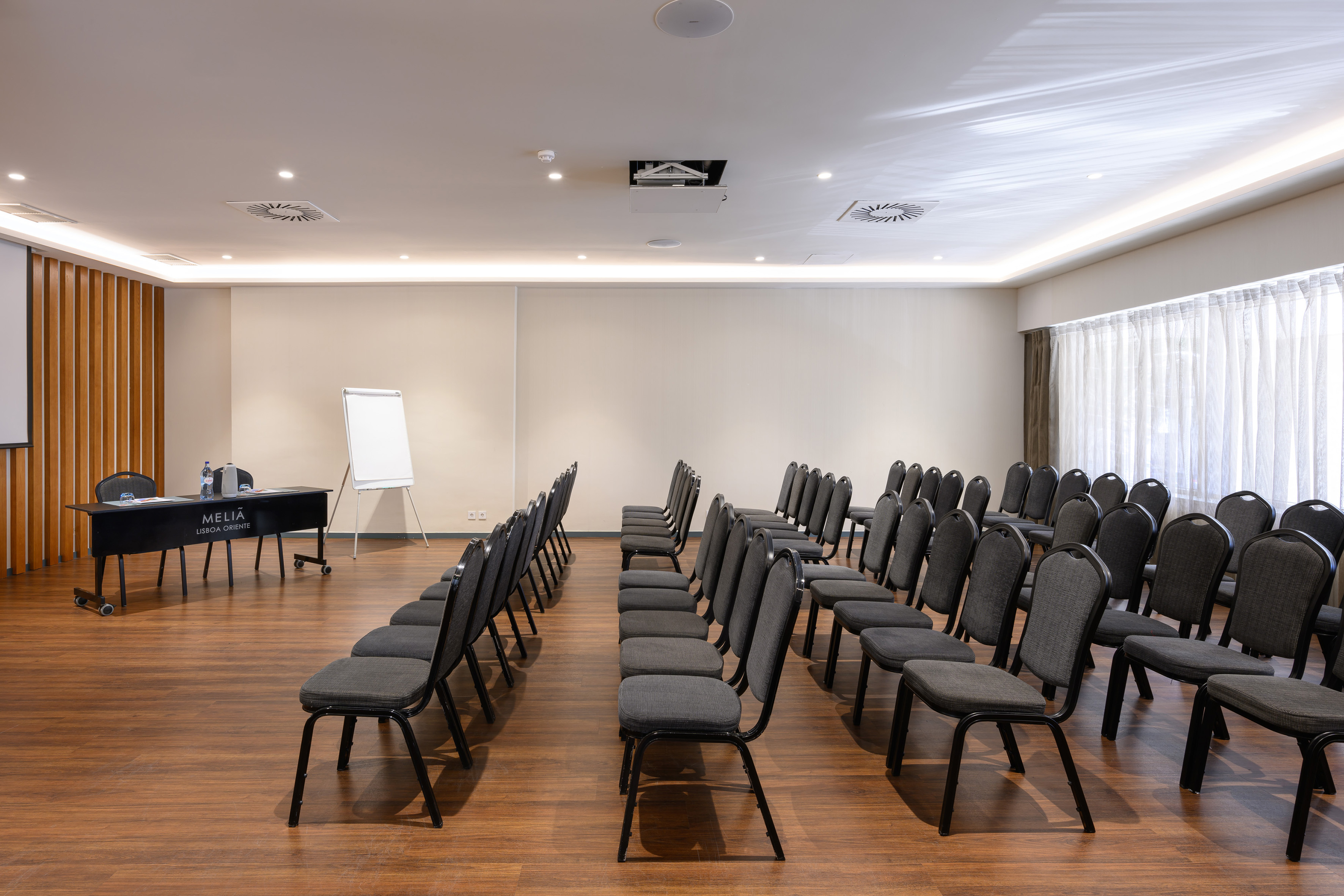 Empty conference room at Meliá Lisboa Oriente with chairs, projector, and whiteboard.