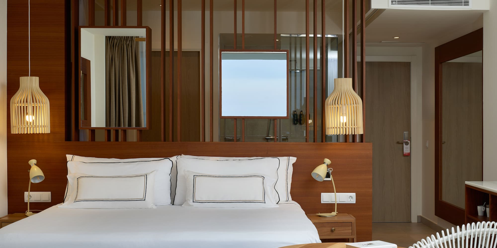 a bed with white sheets and a table in front of a room with a fan