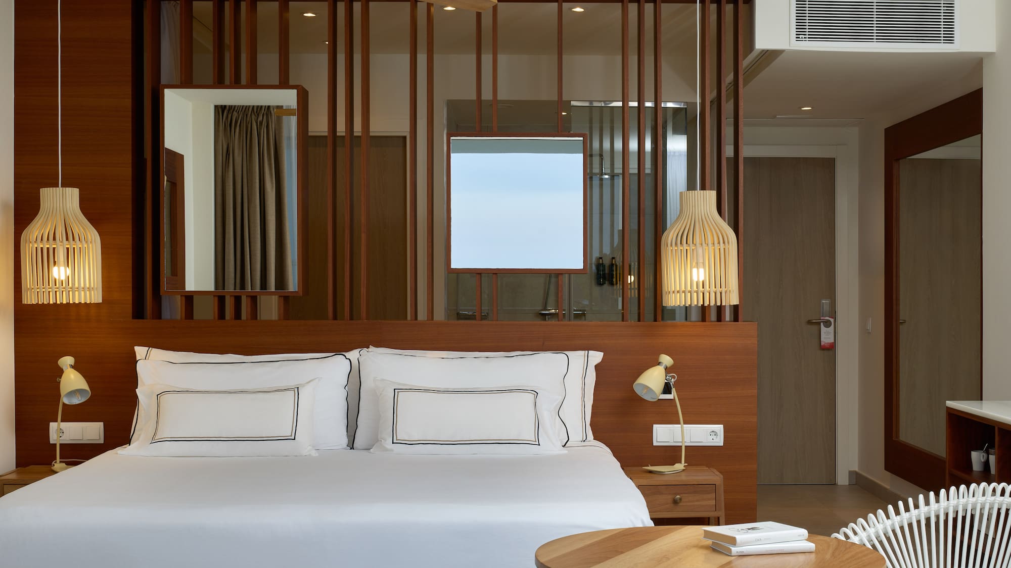 a bed with white sheets and a table in front of a room with a fan