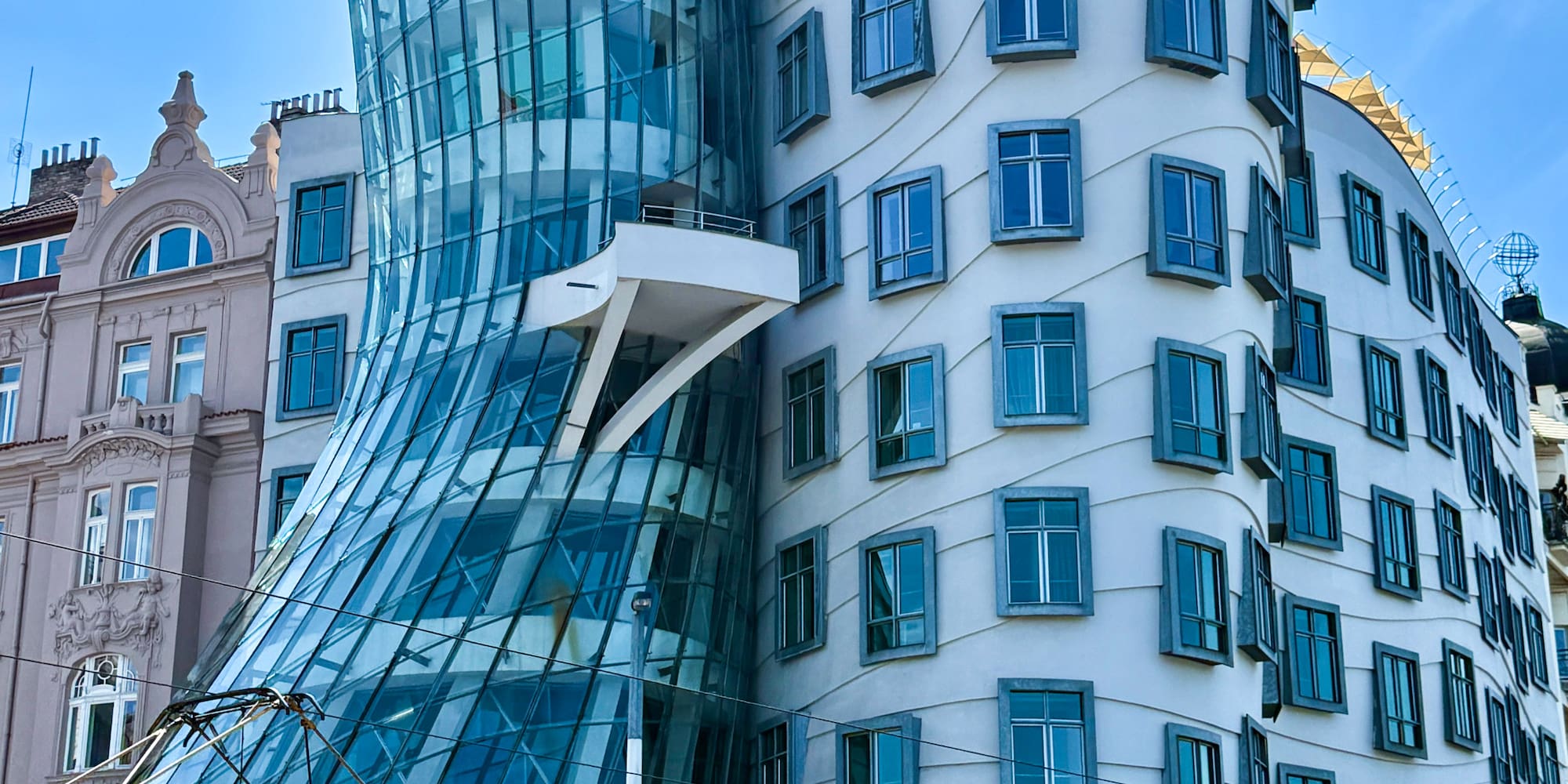 Prague's Dancing House, curved glass and white modern architecture with trams.