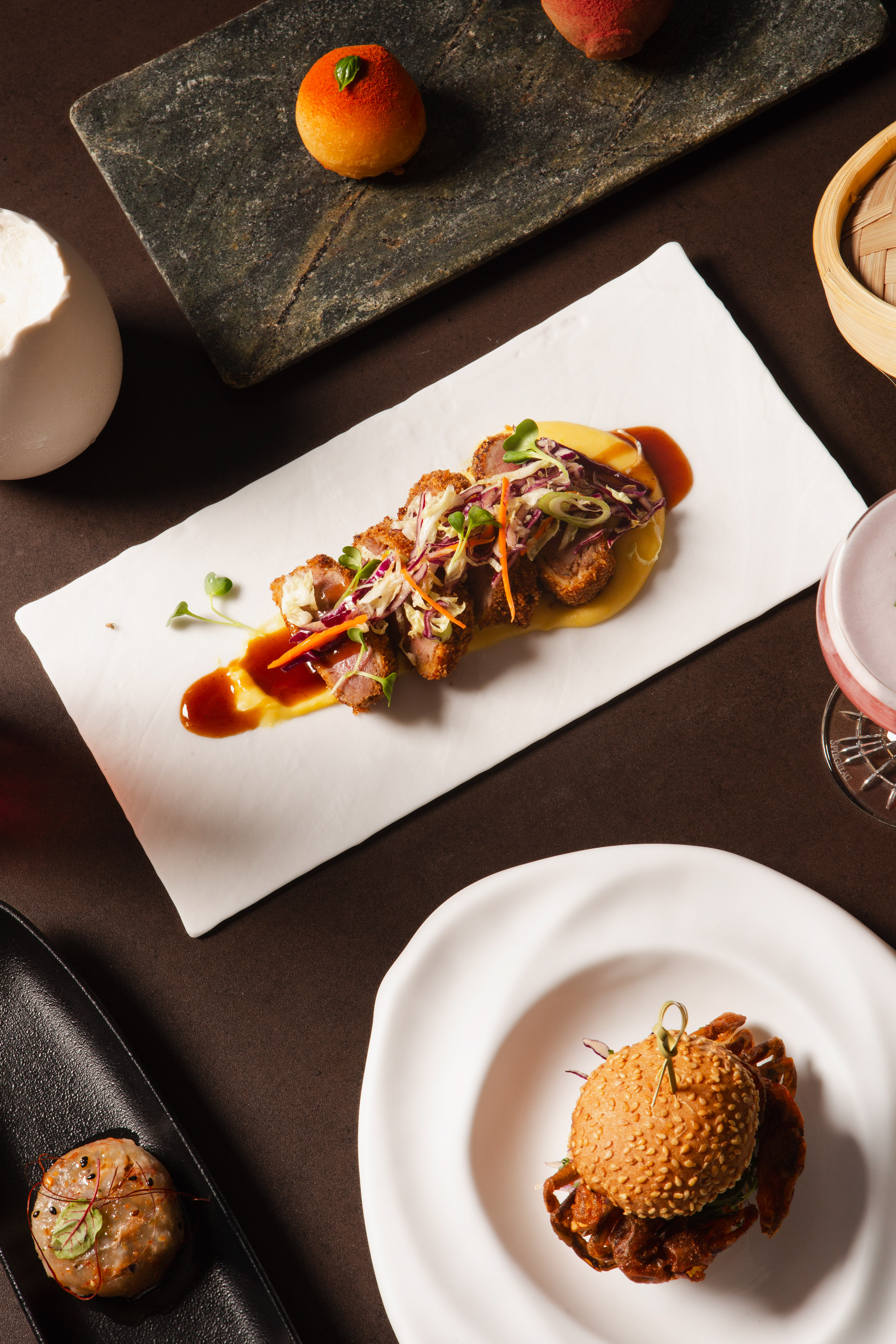 Sliced crispy meat with slaw, soft-shell crab slider, and orange pastry.