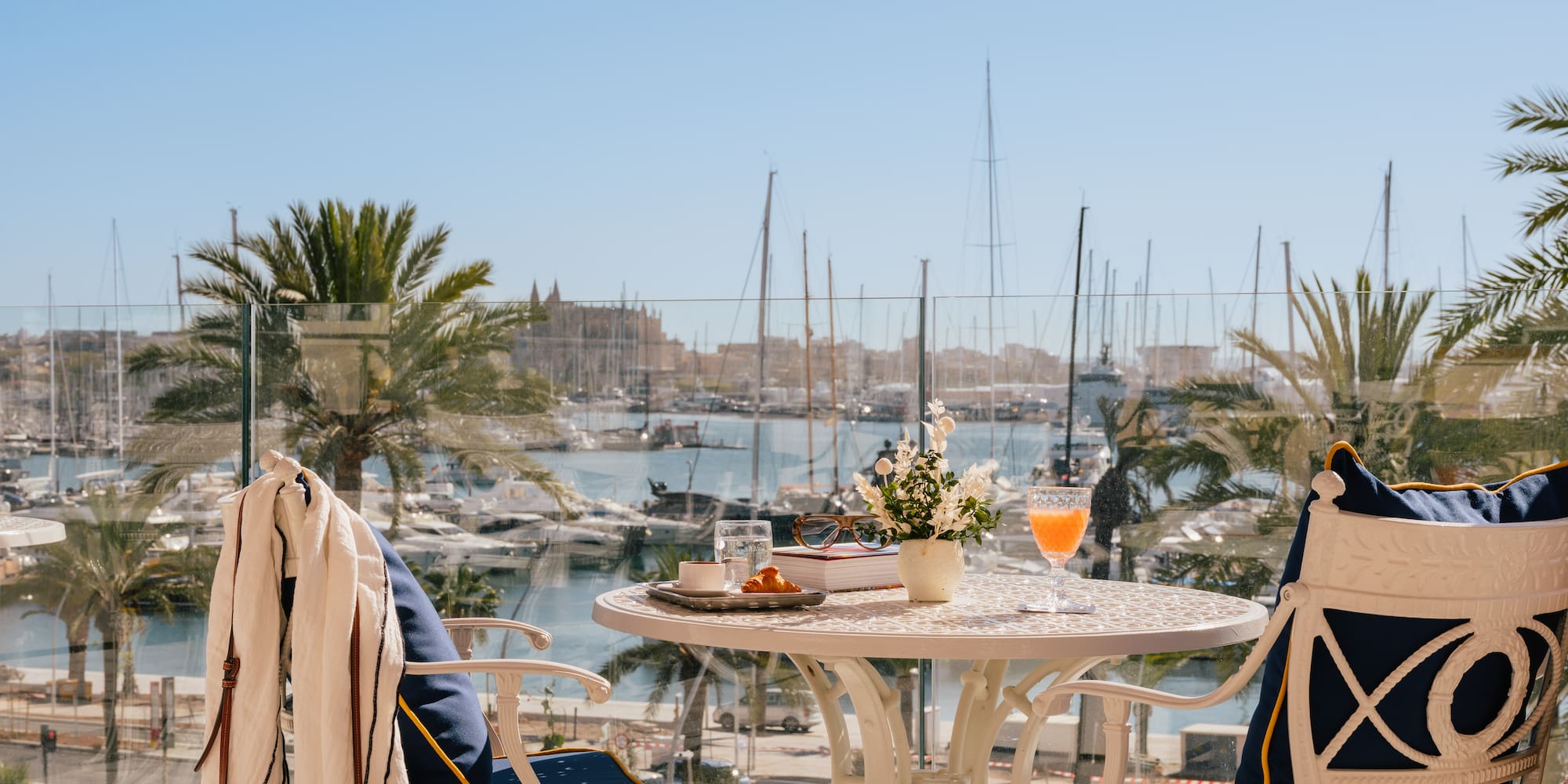a table with a drink and chairs on a balcony overlooking a body of water