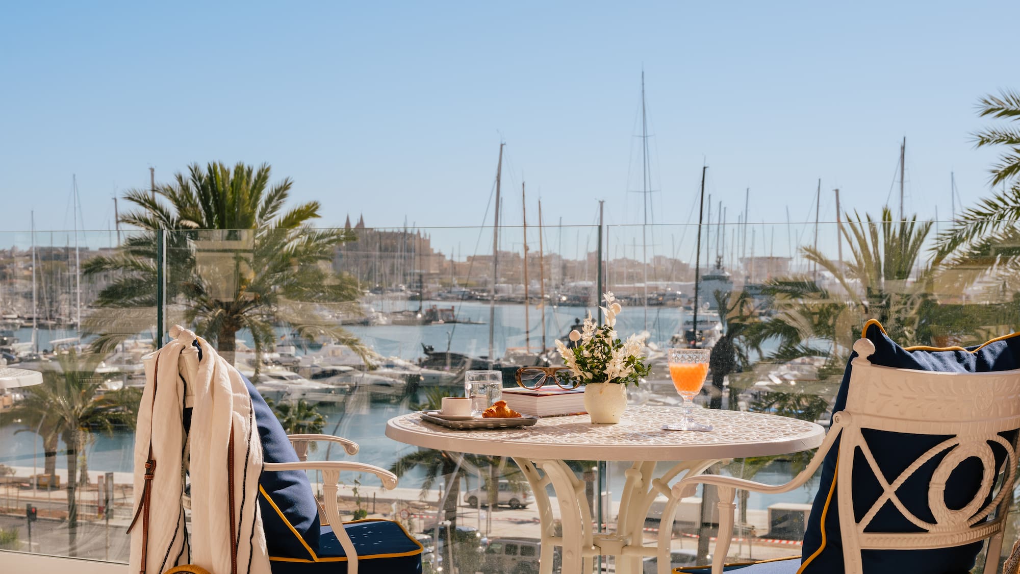 a table with a drink and chairs on a balcony overlooking a body of water