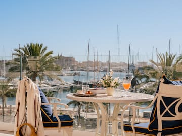 a table with a drink and chairs on a balcony overlooking a body of water