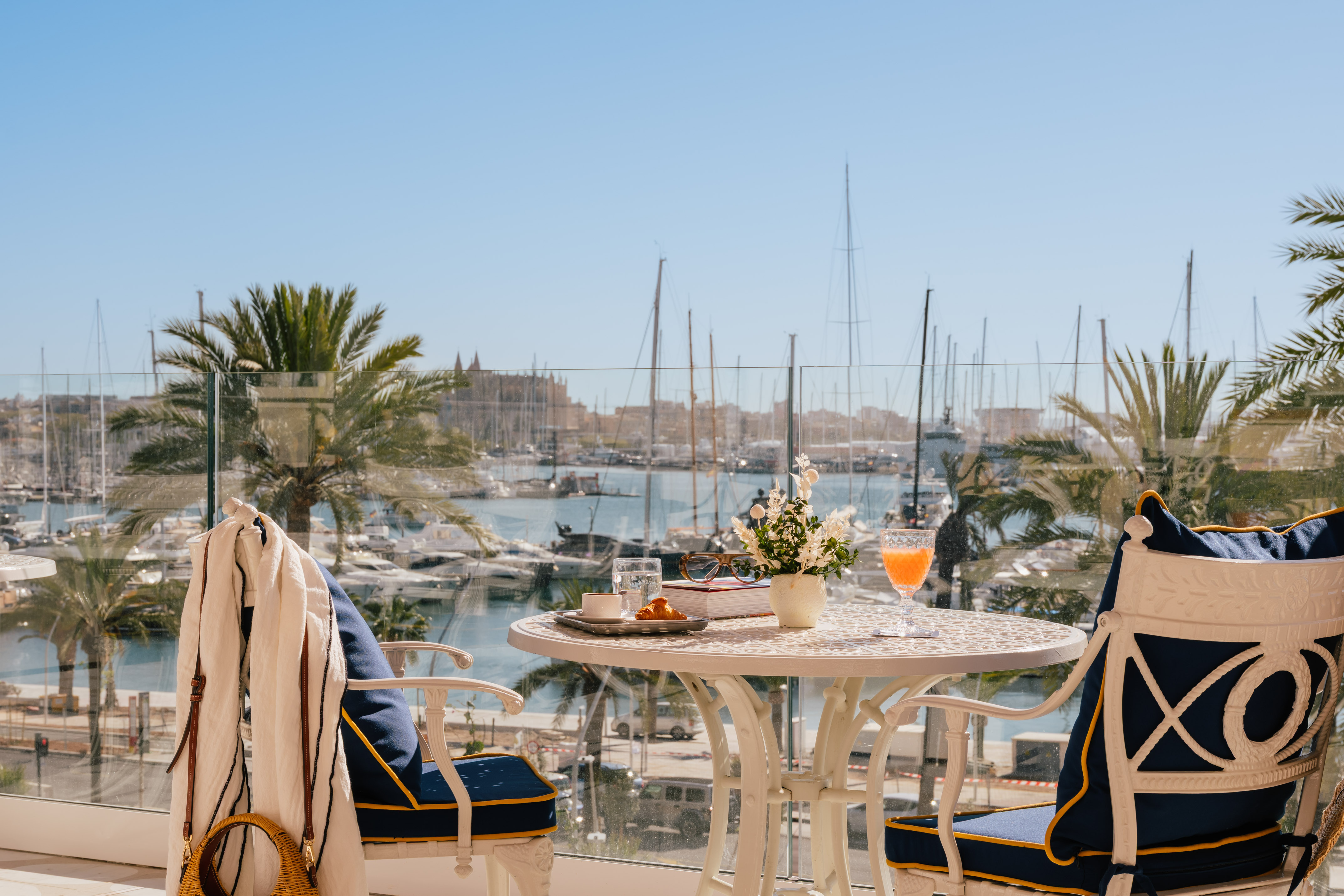 a table with a drink and chairs on a balcony overlooking a body of water