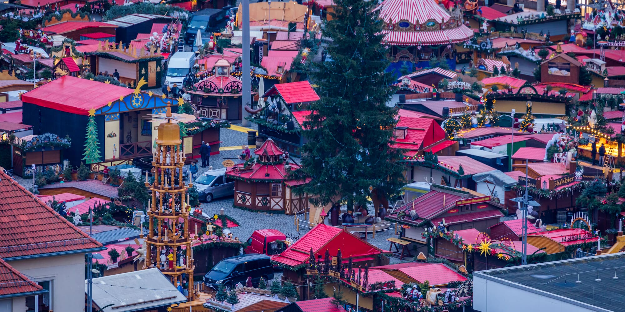 Dresden Christmas market with festive stalls, tall tree, carousel, and pyramid.