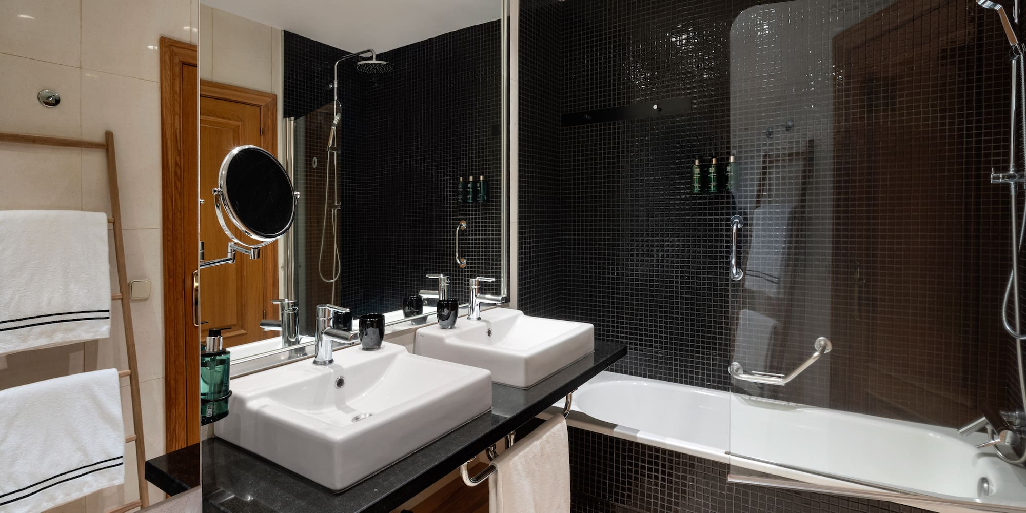 a bathroom with black tile walls and white sinks