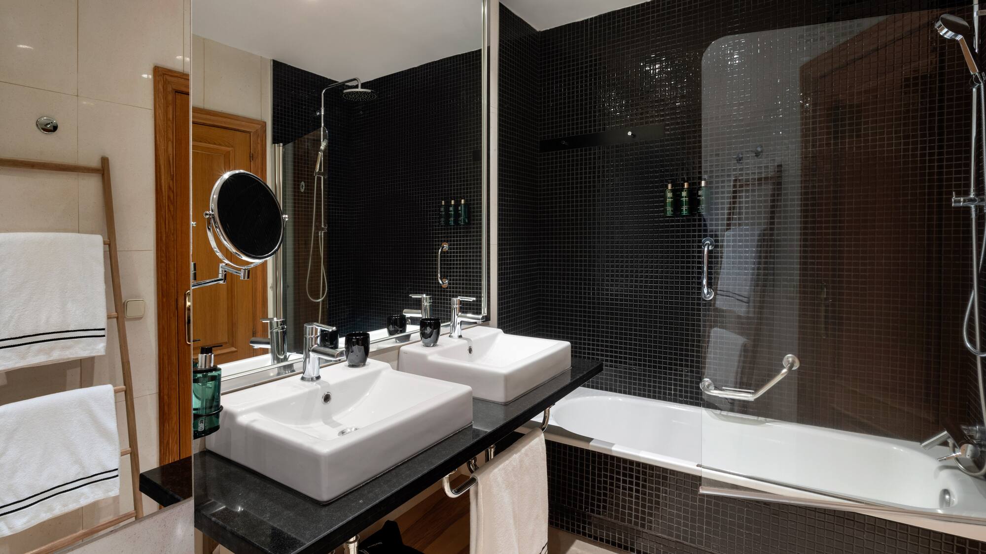 a bathroom with black tile walls and white sinks