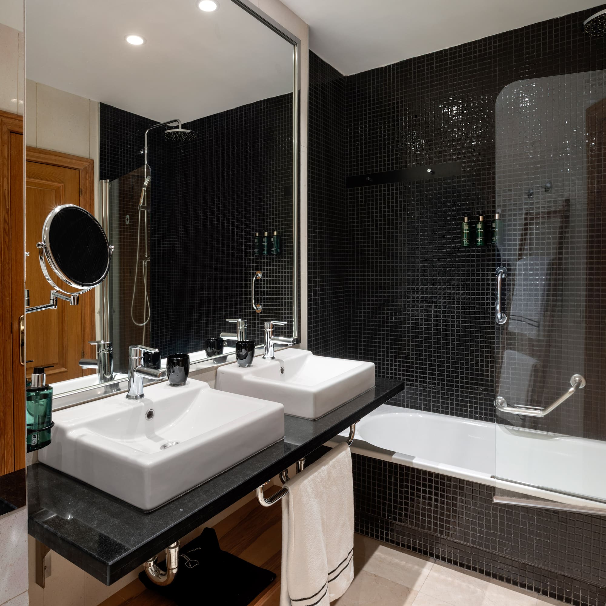 a bathroom with black tile walls and white sinks