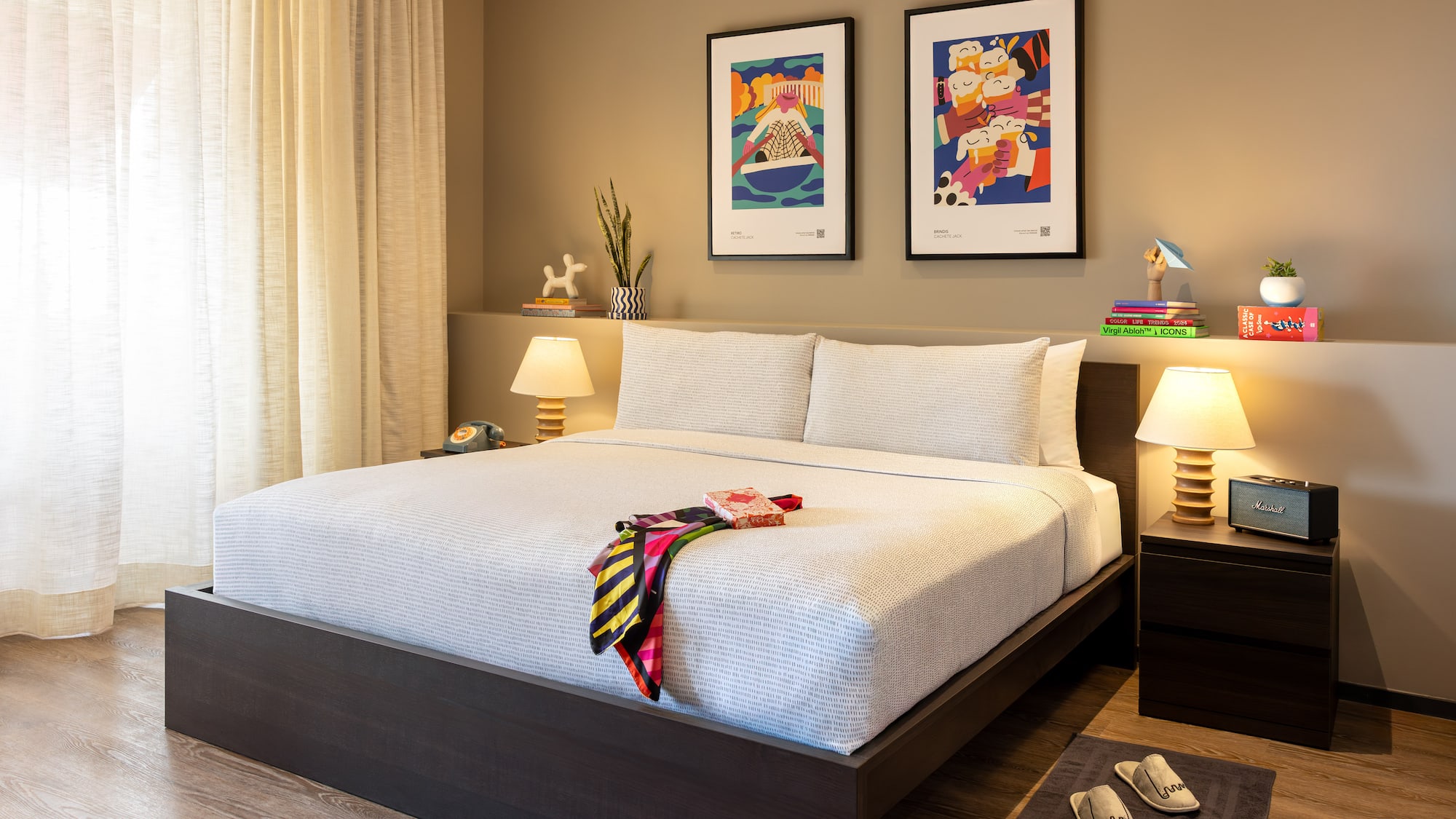 Dormitorio moderno con cama doble, arte, mesitas de noche, lámparas y suelo de madera.